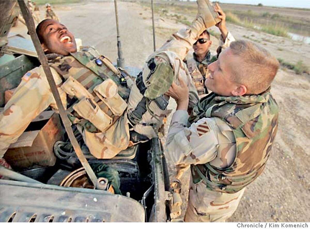 During some down-time at their observation post, Specialist Antoine McNaulty is placed in the trunk of his humvee by Lt. Jason Scott (right) and Sgt James Benson (center) A feature on two soldiers from different San Francisco backgrounds who ended up in a humvee patrolling the Samarra Bypass (one of the most dangerous stretches of Iraq's main north-south artery, Highway 1.) Specialist Antoine McNaulty grew up the oldest of three children to a single mother in Hunter's Point. 1st Lt. Jason Scott worked for a "boutique PR firm" during the dot-com boom working for clients like Apple Computer and Pixar. Scott lived on Geary near Van Ness in the years when a Tenderloin District apartment could fetch a high rent. The Soldiers are from C (Chaos) Company of the 3-69th Armored Battalion of the First Brigade, 42nd Infantry Division. San Francisco Chronicle photo by Kim Komenich