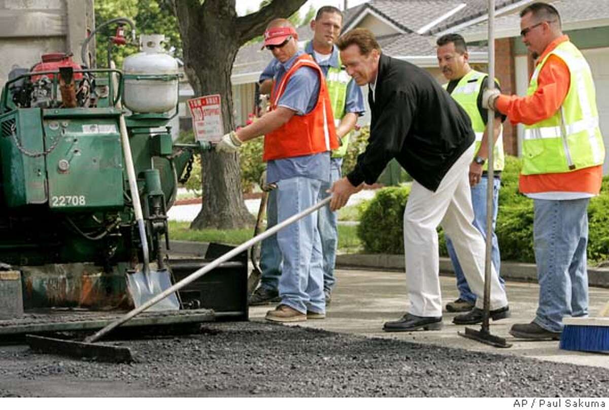 Calif. Gov. Arnold Schwarzenegger uses a tool to help grade a road in San Jose, Calif., as road workers watch, Thursday, May 26, 2005. Schwarzenegger discussed full funding of Proposition 42 transportation funds in his revised budget. (AP Photo/Paul Sakuma)