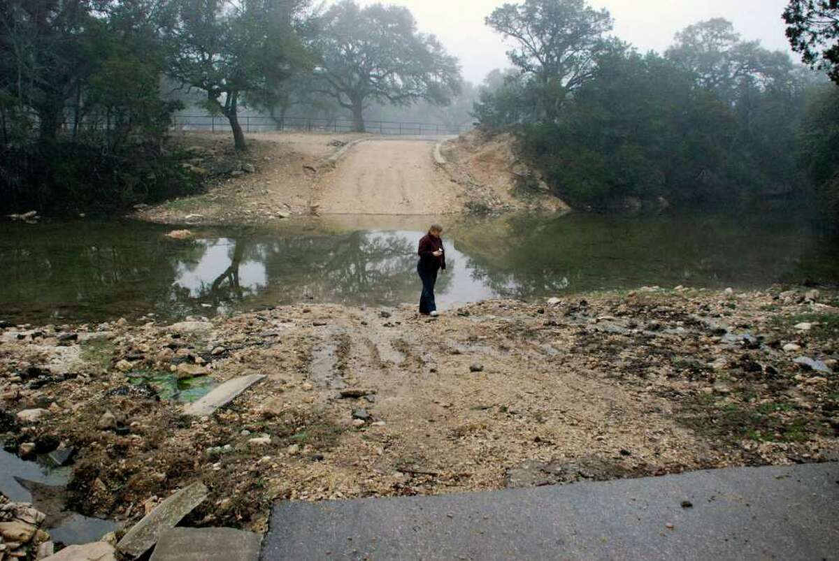 Bexar County employees inspecting Clearwater Ranch on a rainy day on Feb. 2, 2010. One of these photos is of the washed-out bridge. COURTESY PHOTO