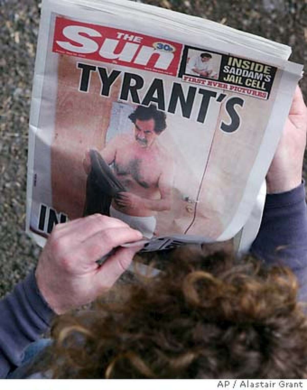 ** THIS IMAGE MUST BE USED IN ITS ENTIRETY ** A man looks at the front page of the British tabloid newspaper 'The Sun', carrying a photo showing former Iraqi president Saddam Hussein, clad only in white briefs, folding a pair of trousers, in London, Friday May 20, 2005. The Sun said it obtained a number of photos from "U.S. military sources", and a statement issued by the U.S. military in Baghdad said the photos violated military guidelines " and possibly Geneva Convention guidelines for the humane treatment of detained individuals". It said the source of the photos was unknown, but they were believed to have been taken more than a year ago.(AP Photo/Alastair Grant)
