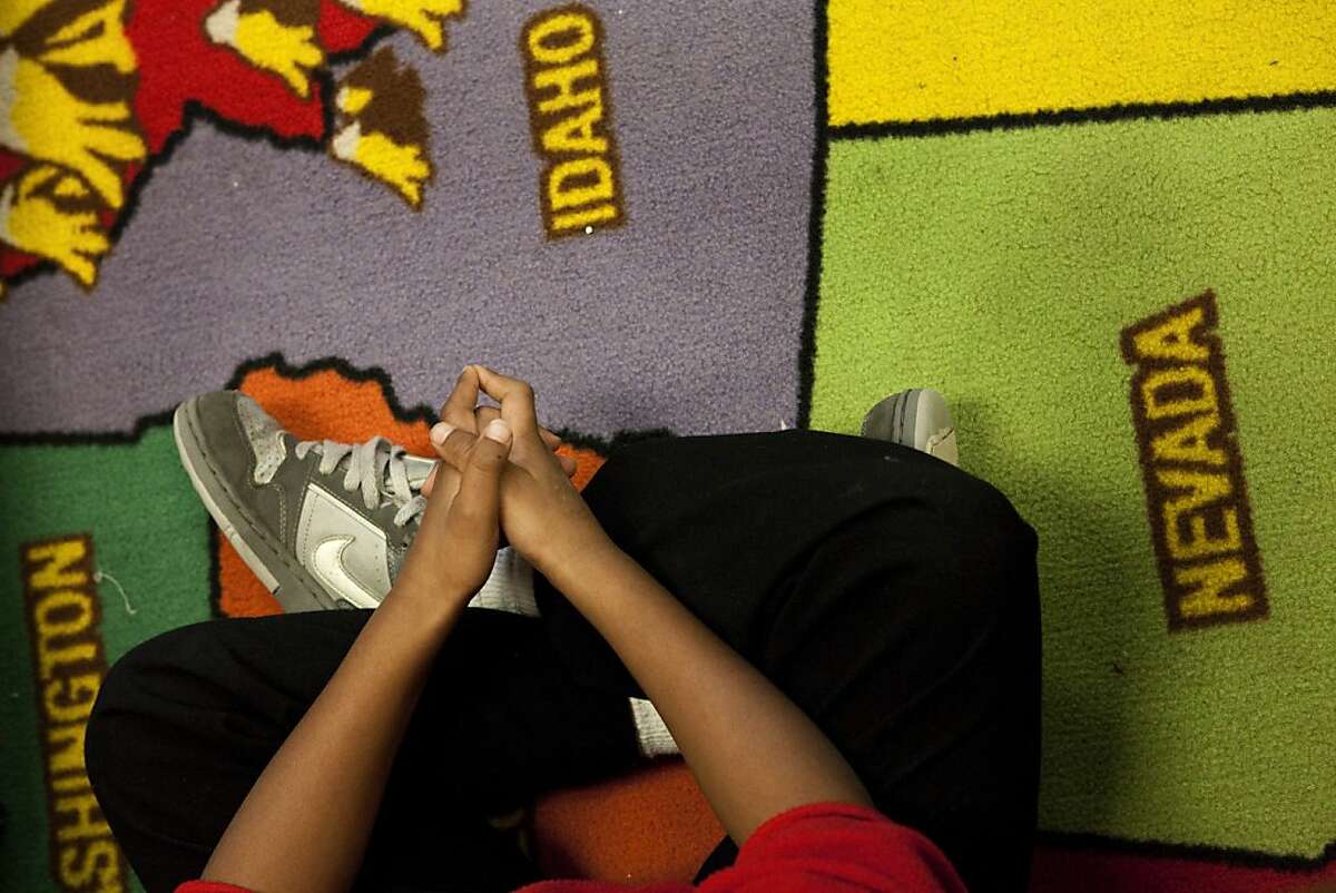 Devantay Williams sits on a rug with the geography of the United States while his teacher, Ms. Simmons, guides the 3rd grade class in learning vocabulary about the solar system at Star King Elementary on Friday, January 20, 2011 in San Francisco, Calif.