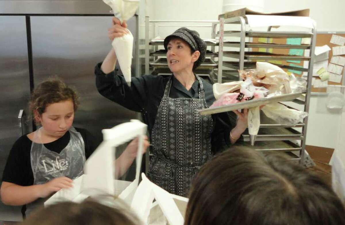 Michelle Klem, owner of CakeSuite in Westport, shows a group of 9- and 10-year-old girls how to use a pastry bag to frost their cupcakes Friday at a birthday party inspired by the Food Network's "Cupcake Wars" show.