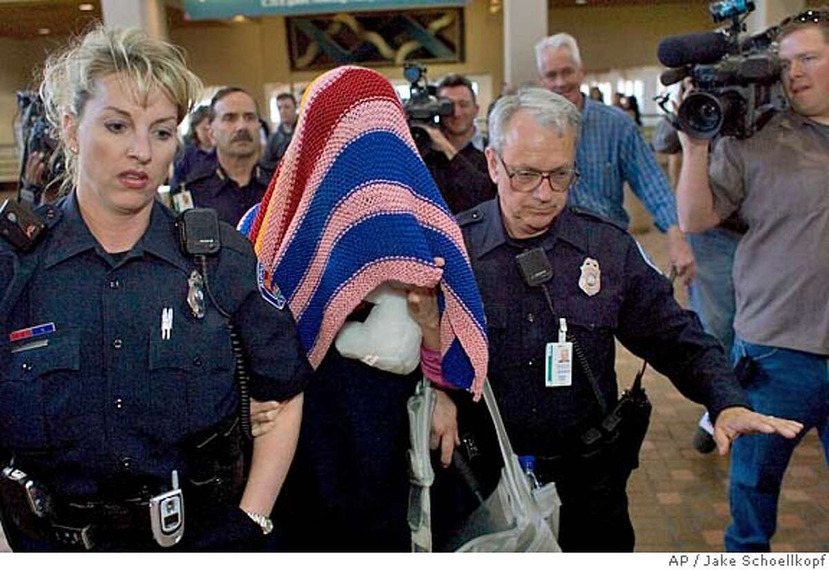 Police officers escort a blanket covered Jennifer Wilbanks through the Albuquerque Sunport, Saturday, April 30, 2005, as she is taken to her flight and back to Atlanta. Wilbanks turned up in Albuquerque late Friday night after she dissapeared last Tuesday, days before her wedding. (AP Photo/Jake Schoellkopf)