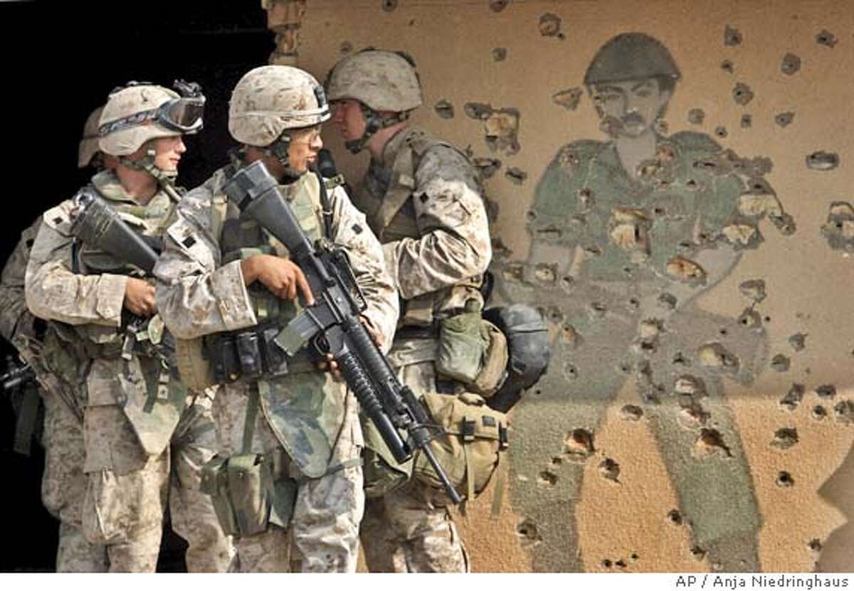 US Marines of the 1st Division pass by a wall painting of an Iraqi Army soldier during training in a former Iraqi army barrack outside Fallujah, Iraq, Thursday, Nov. 4, 2004. U.S. forces are preparing for a major offensive in Fallujah, west of Baghdad, and other Sunni militant strongholds in hopes of curbing the insurgency ahead of January's election. (AP Photo/Anja Niedringhaus)