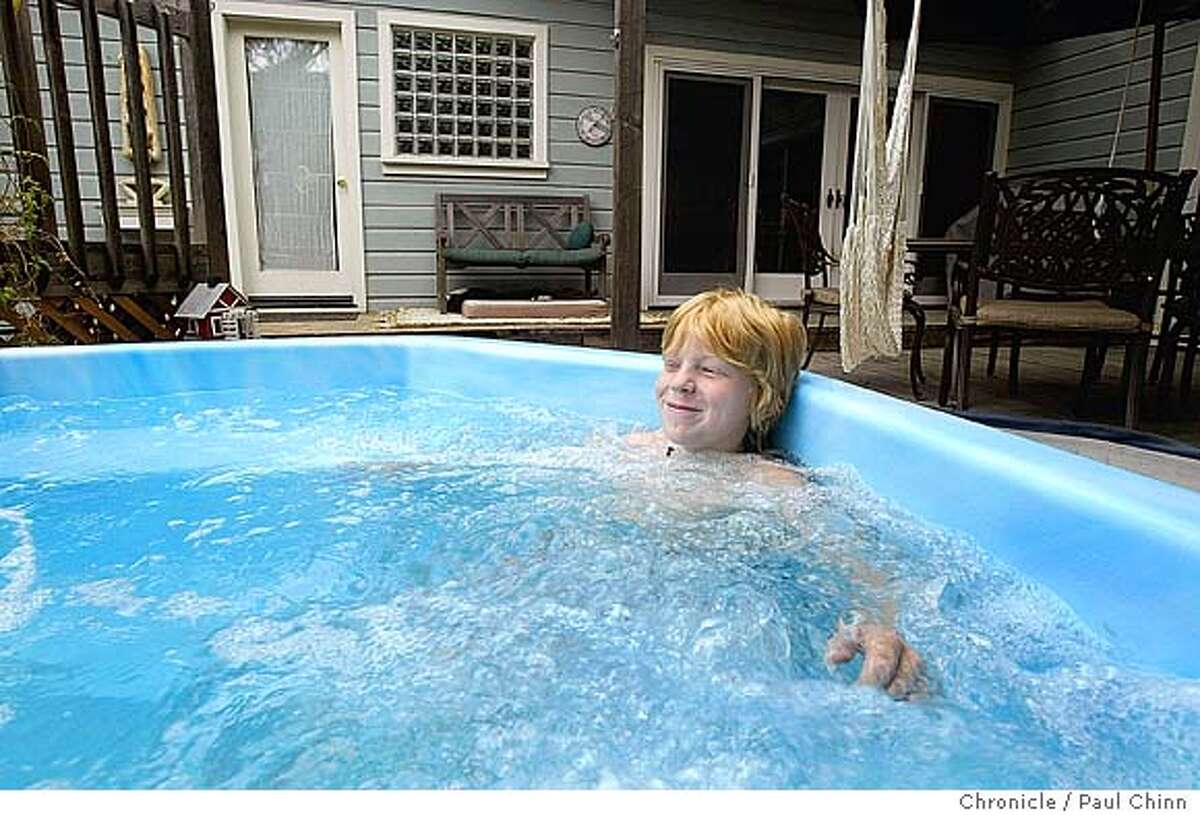 Ten-year-old Chris Wentworth soaks in the family hot tub which is heated and powered by dedicated solar panels on the roof. The Wentworth family green home on 10/16/04 in Alamo, CA. "Green" homes minimize the negative impact on the community and the natural environment; they have solar heating. PAUL CHINN/The Chronicle