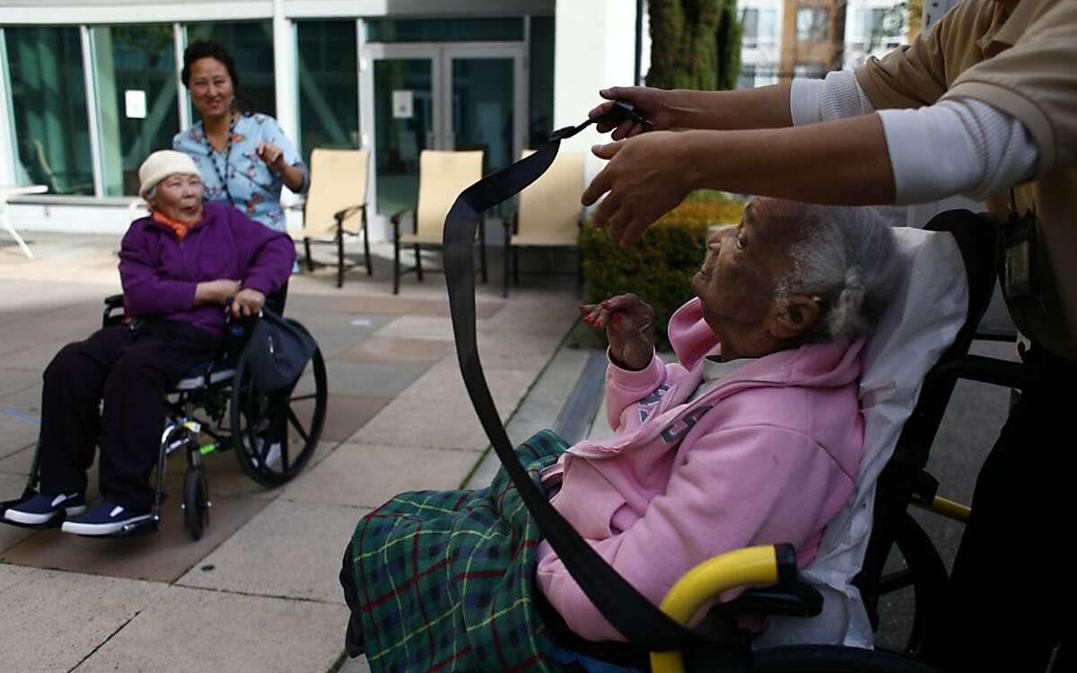Bessie Holloway (second from right) waves good by to CEI client Pung Ja Ha (left) and Teresa Choe (second from left), CEI geriatric aide as she is helped onto a CEI transport van for a trip home by Shee Poy Young (right), CEI driver at the Center for Elders' Independence Downtown Oakland Pace Center on Tuesday, January 24, 2012 in Oakland, Calif.