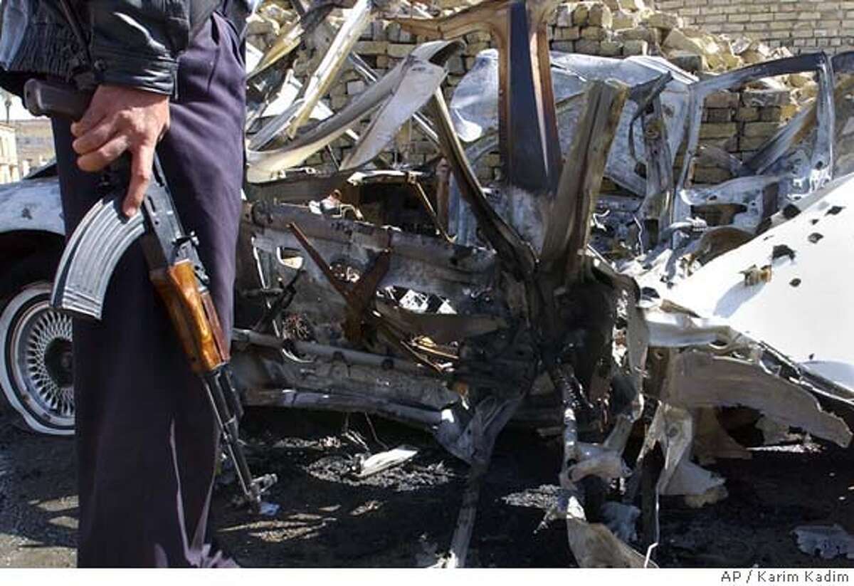 An Iraqi police officer stands near the wreckage after a suicide car bomb exploded, killing one child and wounding at least four people, including a police officer in Baghdad, Iraq Tuesday, March 15, 2005. The bomber was trying to hit a traffic police patrol, police said. Another car bomb targeting a U.S. military convoy exploded on the main road to Baghdad's international airport in the west of the city, wounding two police who were guarding a nearby gas station, police said. Witnesses said some U.S. troops were also wounded in the second blast. (AP Photo/Karim Kadim)