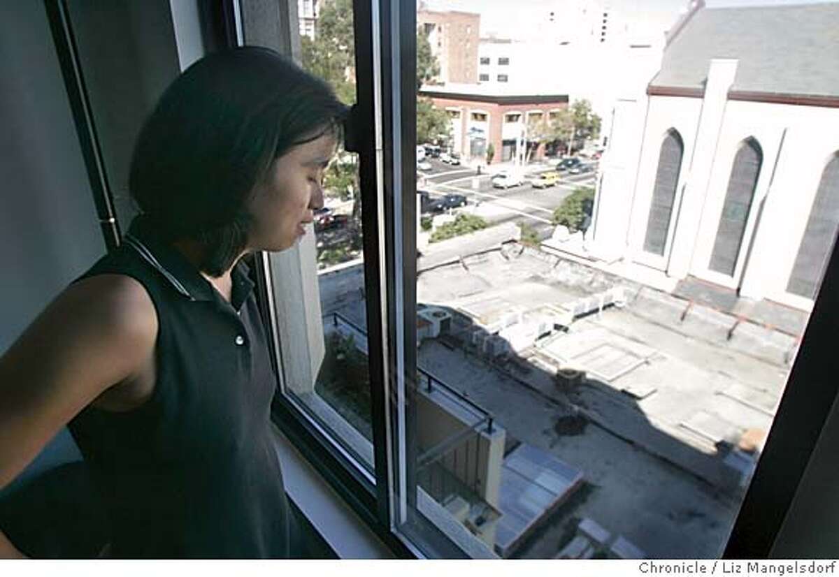 Event on 9/8/04 in San Francisco. Condo owner Christianne Pang looks out her window onto the current building which is occupied by a Buddhist Temple. On the right is St. Luke's Episcopal Church, which will have it's stained glass windows blocked by the project. Condo owners and St. Luke's Episcopal Church fight Walter Wong and his client, a buddhist temple on Van Ness over the size of a proposed building, that will block light and views to both the condo and the church. Liz Mangelsdorf / The Chronicle