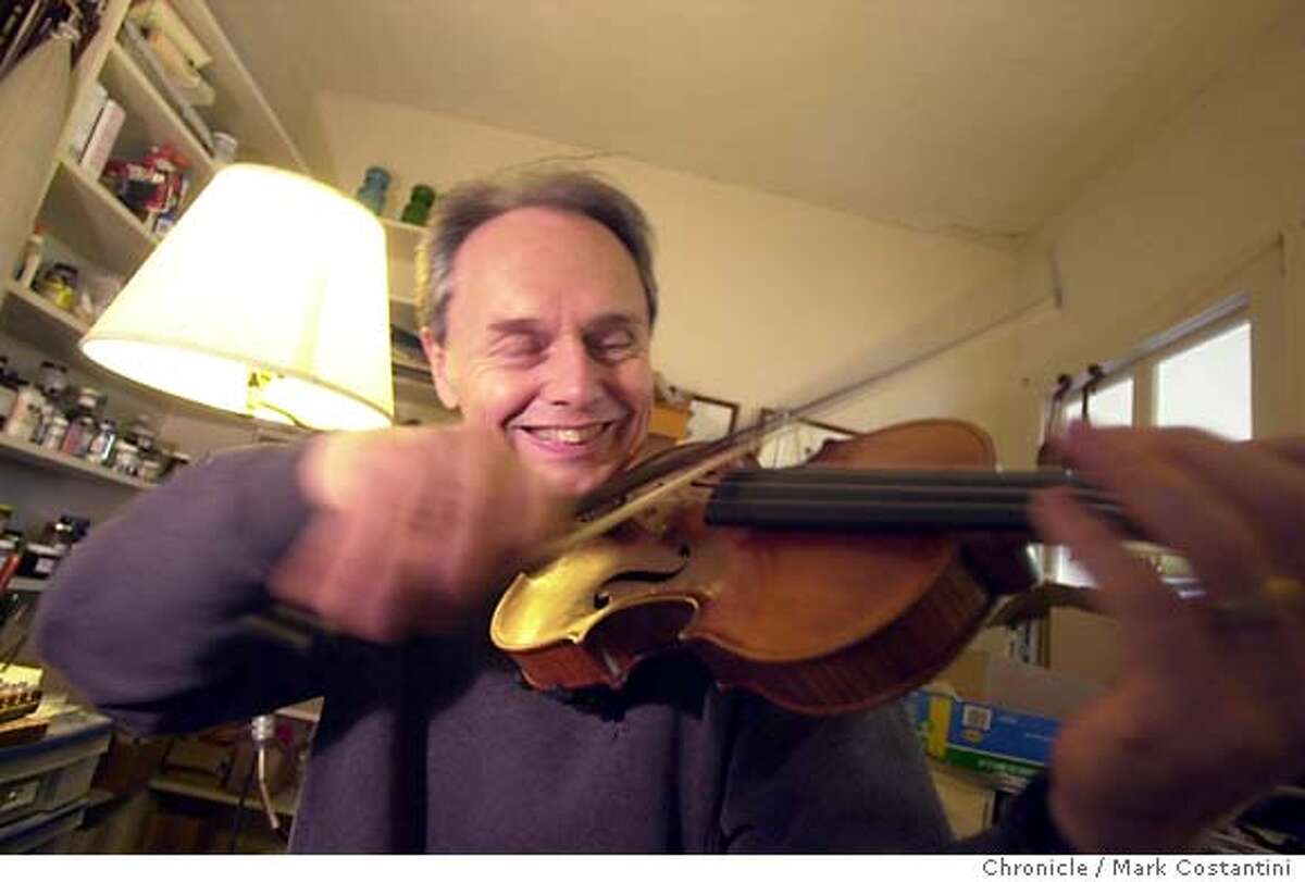 Patrick , expert violin maker in his studio. He's having fun playing one he made for Kronos Quartet member. 7/15/04 in BERKELEY. Chronicle Photo by Mark Costantini