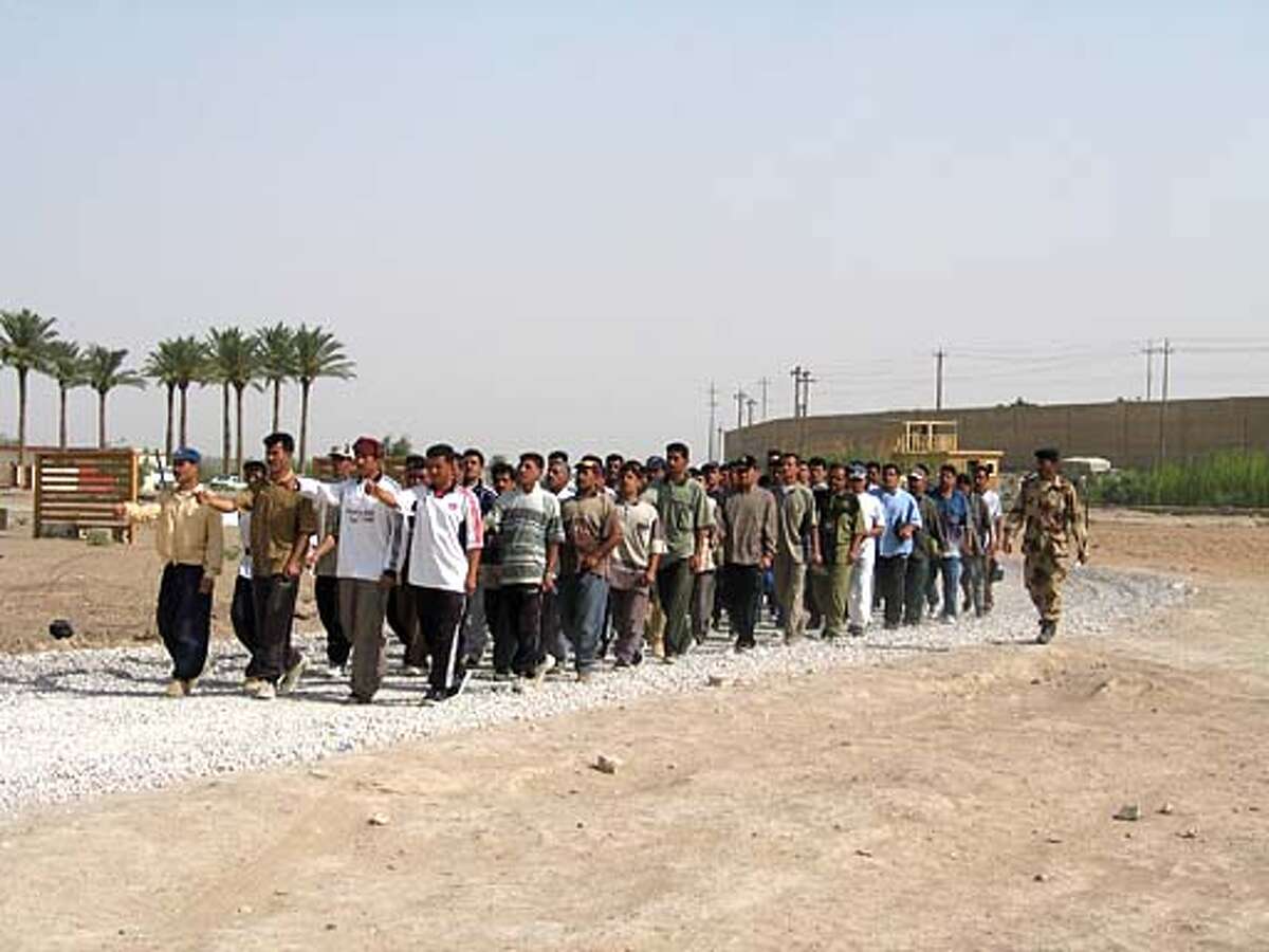 A group of about Iraqi 50 men practice marching in formation in civilian clothes in Ramadi. Chronicle photo by John Koopman