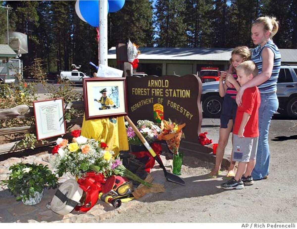 Ashlee Wilkes, 15, right, puts her arms around her sister Brittian, 9, and brother Bailey, 5, as they have a quiet moment at a memorial honoring California Department of Forestry firefighter Eva Schicke in front of the CDF's Arnold Forest Fire Station in Arnold, Calif., Monday, Sept. 13, 2004. Schicke, 24, of Arnold, was killed Sunday after she and six other firefighters were dropped into rugged terrain just outside Yosemite National Park and overrun by the flames. Her body was recovered Monday morning. Her six crew members were released after being treated for injuries they suffered while trying to cut off the fire's advance through the Tuolumne River Canyon.(AP Photo/Rich Pedroncelli) BRITTIAN IS CQ