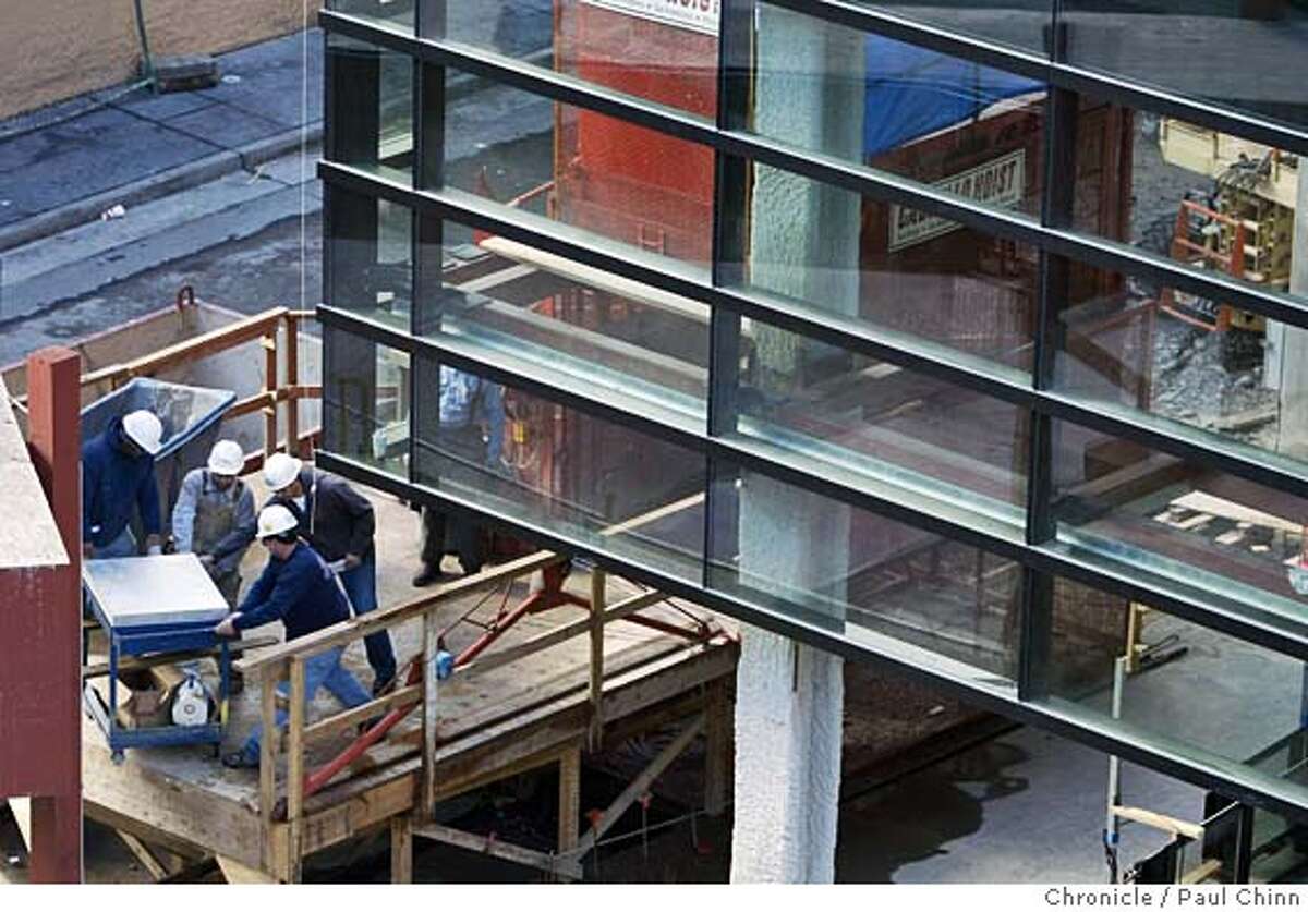 bloomingdale19_022_pc.jpg Construction workers (lower left) remove material beneath newly installed glass panels. Several large glass panels have been attached to the Mission St. facade of the Bloomingdale's project on 2/18/05 in San Francisco, CA. PAUL CHINN/The Chronicle MANDATORY CREDIT FOR PHOTOG AND S.F. CHRONICLE/ - MAGS OUT