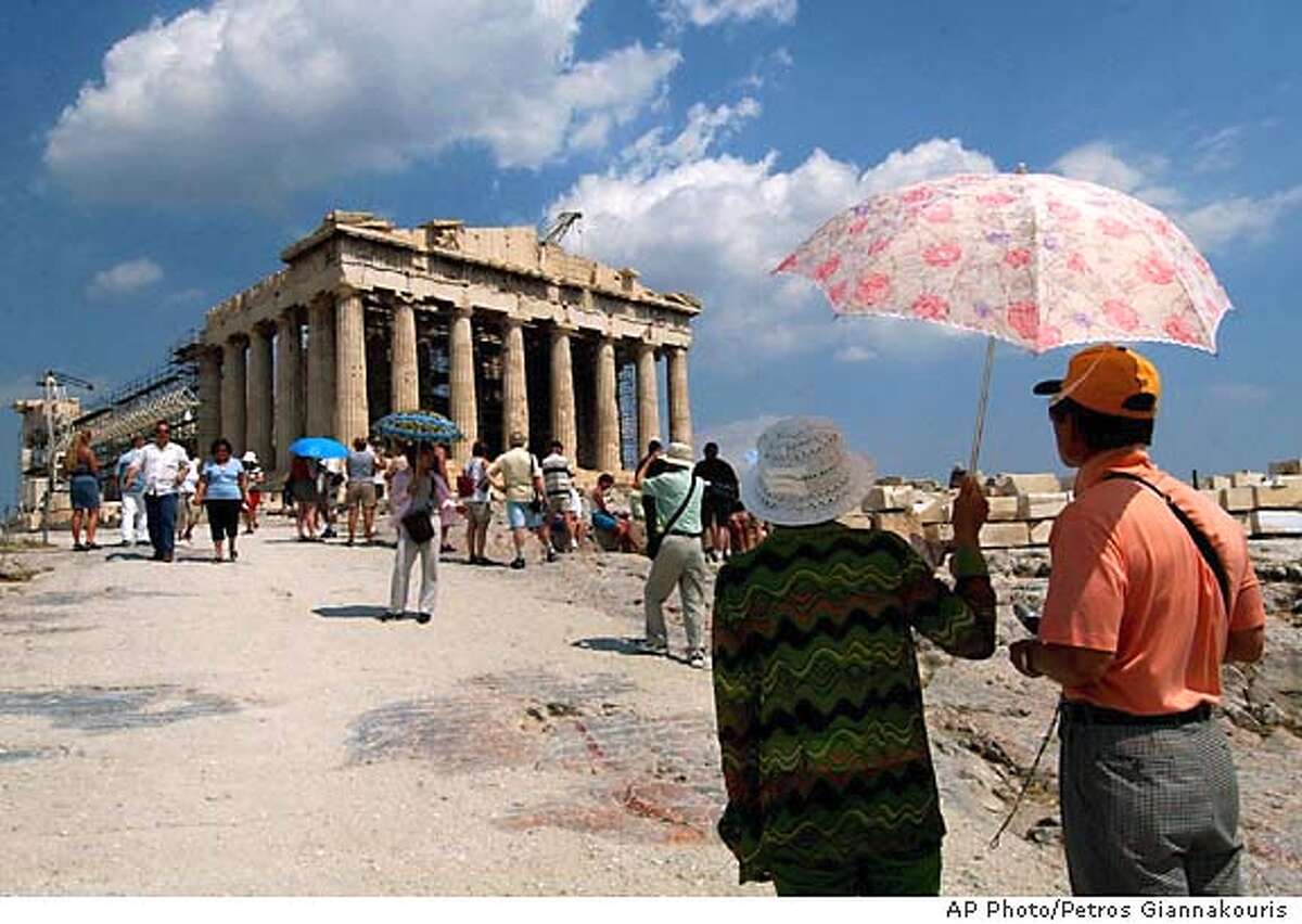 Tourists admire the Parthenon temple on the ancient Acropolis hill in Athens, June 24, 2004. Scaffolding propping up parts of the 2,500-year-old hill top temple will remain in the place during the Aug. 13-29 Olympic Games, after officials conceded that a massive restoration project cannot meet the symbolic deadline. (AP Photo/Petros Giannakouris)