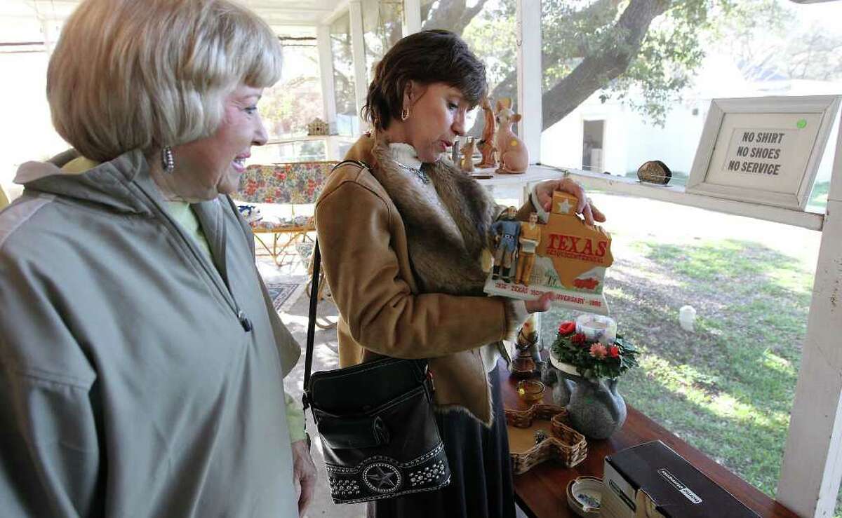 Kathleen Carter (center), former Alamo Committee Chair, looks at a Texas Sesquicentennial decanter with Tookie Walthall (left), past President General of Daughters of the Repubic of Texas at the estate sale.