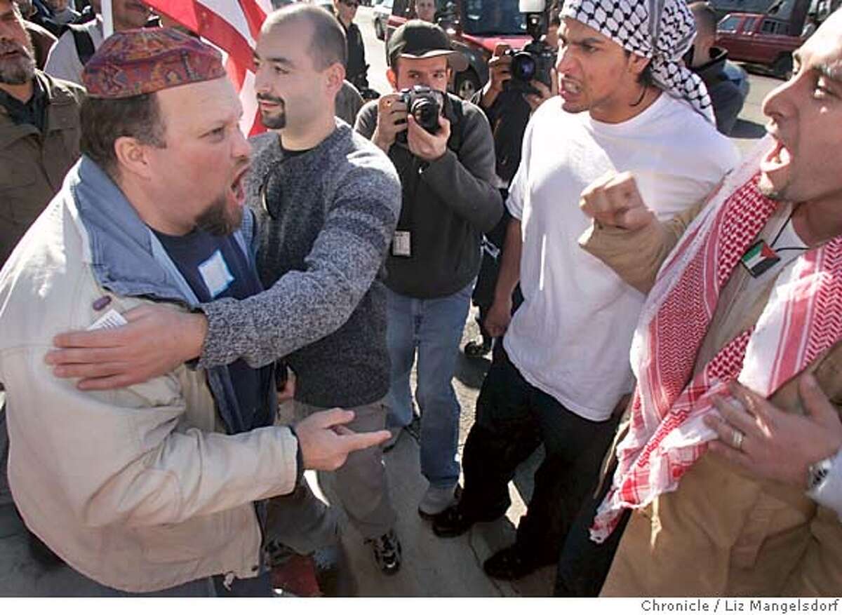 Event on 1/16/05 in Berkeley. Daniel Neves, far left, an Israel supporter, and Shakir Wahhad, far right(back half of head cut off in frame), a Palestinian supporter, are seperated as they confront each other at the rally. Police eventually seperated the two groups of supporters.The israel Action Committee of the East Bay holds a Rally against Global Terrorism at Martin Luther King Park in Berkeley. On display was Bus 19, which was blown-up by a suicide bomber Jan. 29th, 2004 in Jerusalam. Supporters of Palestinians also held a rally, mostly contained across the street from the park. Liz Mangelsdorf / The Chronicle