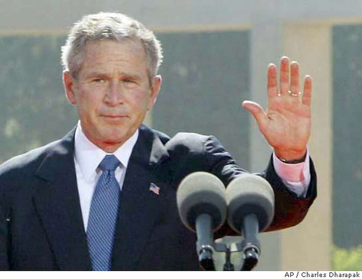 U.S. President George W. Bush, right, waves as French President Jacques Chirac applauds after Bush spoke at the ceremony at the American Cemetery in Normandy at Colleville-sur-Mer, France, Sunday, June 6, 2004. (AP Photo/Charles Dharapak)