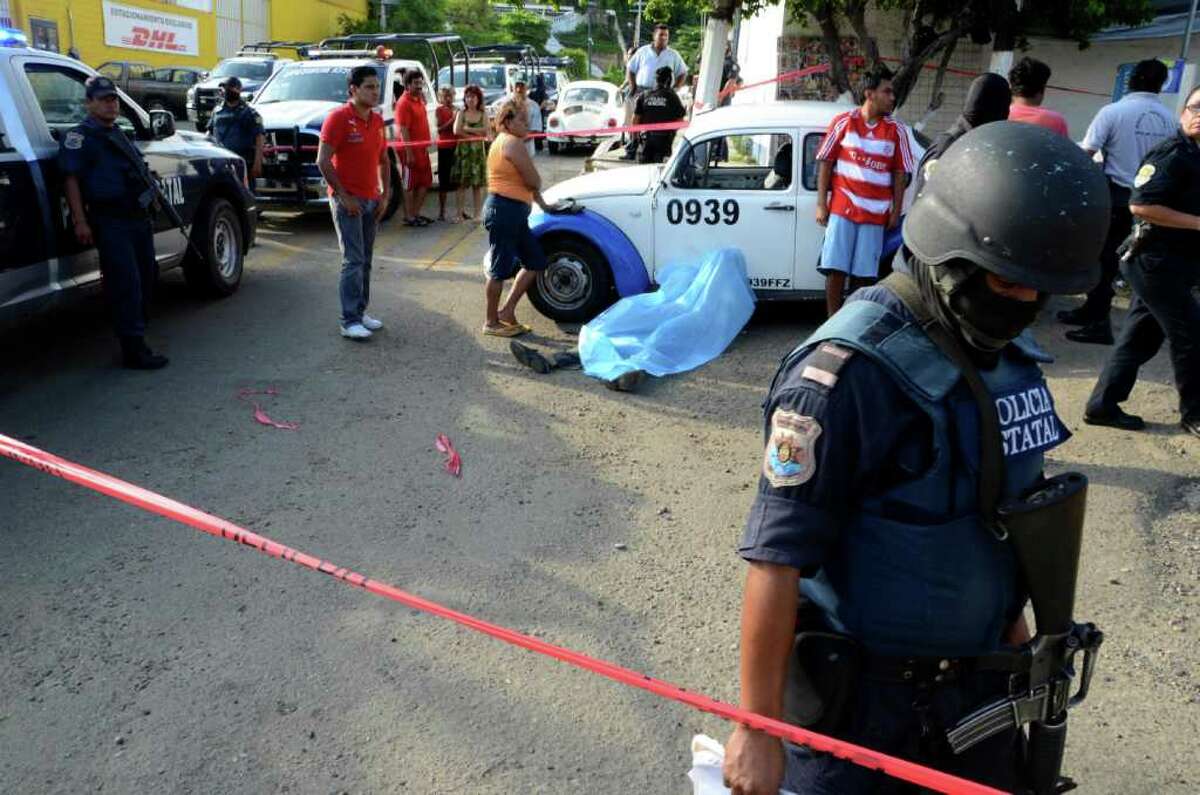 A police officer inspects the crime scene where a man was shot dead in the Pacific resort city of Acapulco, Mexico, Friday Aug. 5, 2011. The city of Acapulco has been hit by violence as drug gangs continue to battle for control of the region.