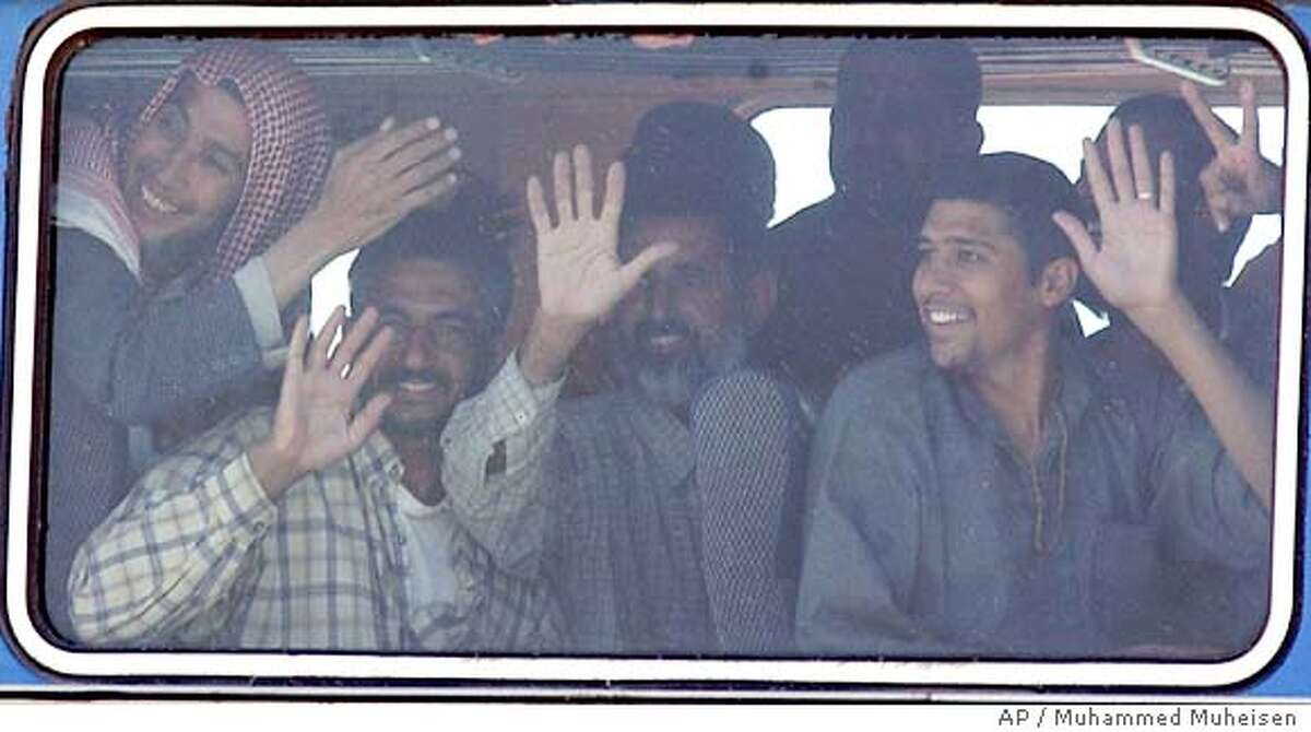 Released Iraqi detainees wave at relatives and friends from the window of the bus while leaving Abu Ghraib prison, outside Baghdad, Iraq, Friday, May 14, 2004. More than 300 Iraqi detainees were released from the infamous Abu Ghraib prison on Friday, a day after U.S. Defense Secretary Donald H. Rumsfeld made a surprise visit and insisted the Pentagon did not try to cover up abuses there. (AP Photo/Muhammed Muheisen)