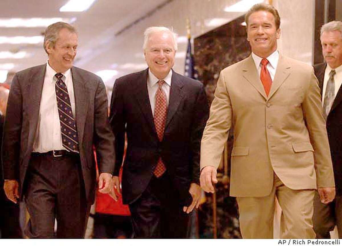 Gov. Arnold Schwarzenegger, right, accompanied by University of California President Robert Dynes, left, and Education Secretary Richard Riordan, center, walk to a Capitol news conference where he announced an agreement with state university officials on funding cuts and enrollment caps, held in Sacramento, Calif., Tuesday, May 11, 2004. Schwarzenegger's plan, which needs approval by the Legislature, would cut in half a proposed 40 percent hike in fees imposed on graduate students while raising otherstudent fees by 10 percent over three years.(AP Photo/Rich Pedroncelli)