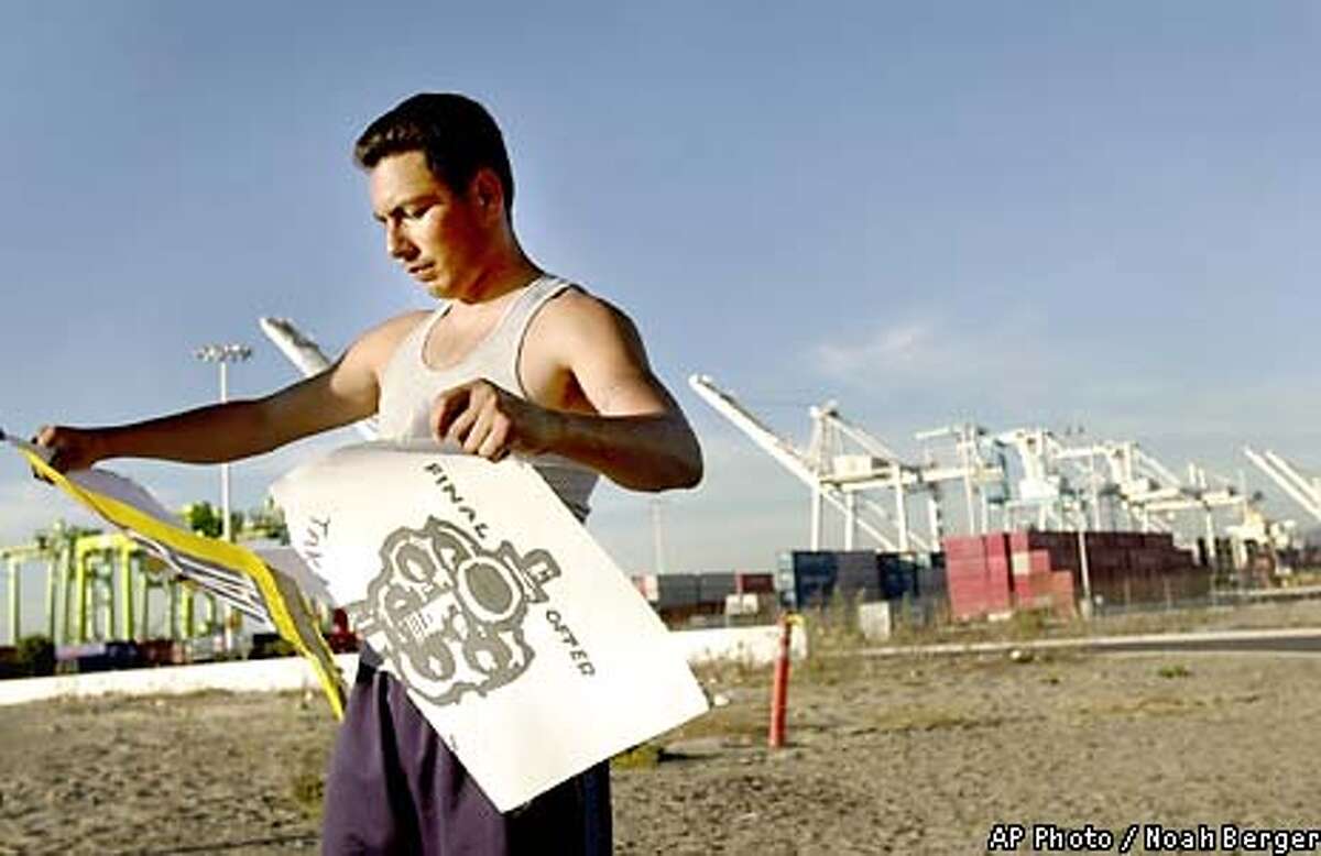Basheem Allah, a member of the International Longshore and Warehouse Union, tears down picket signs outside the TraPac shipping terminal in Oakland, Calif., Tuesday, Oct. 8, 2002. A federal judge approved President Bush's request Tuesday to reopen West Coast ports, ending a caustic 10-day labor lockout that has cost the fragile U.S. economy $1 billion to $2 billion a day. (AP Photo/Noah Berger)