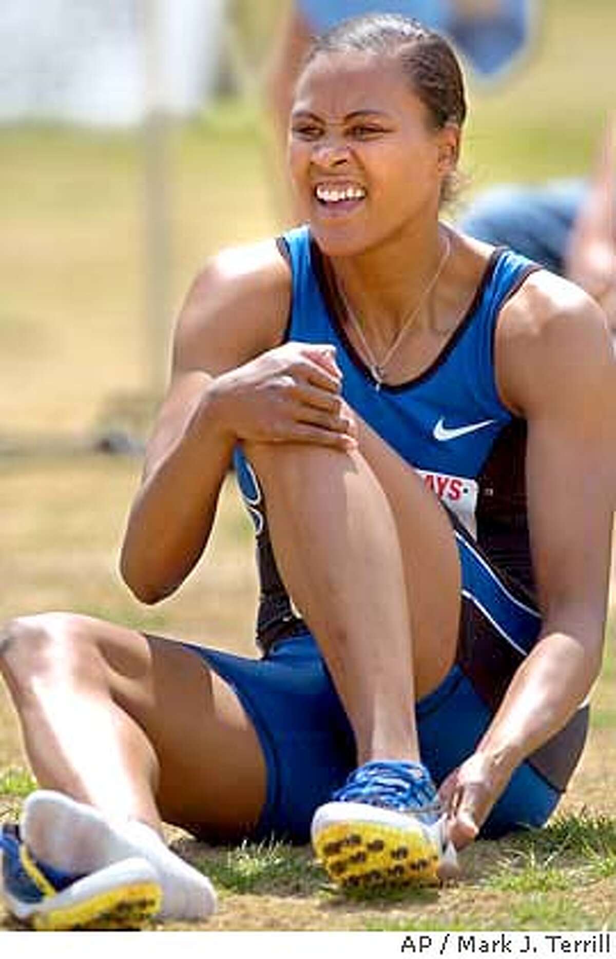 Marion Jones takes her shoes off after the Women's 200 Meter Dash Invitational at the Mt. SAC Relays, Sunday, April 18, 2004, at Mt. San Antonio College in Walnut, Calif. Connie Moore won the race while Jones finished fourth with a time of 22.02. (AP Photo/Mark J. Terrill)