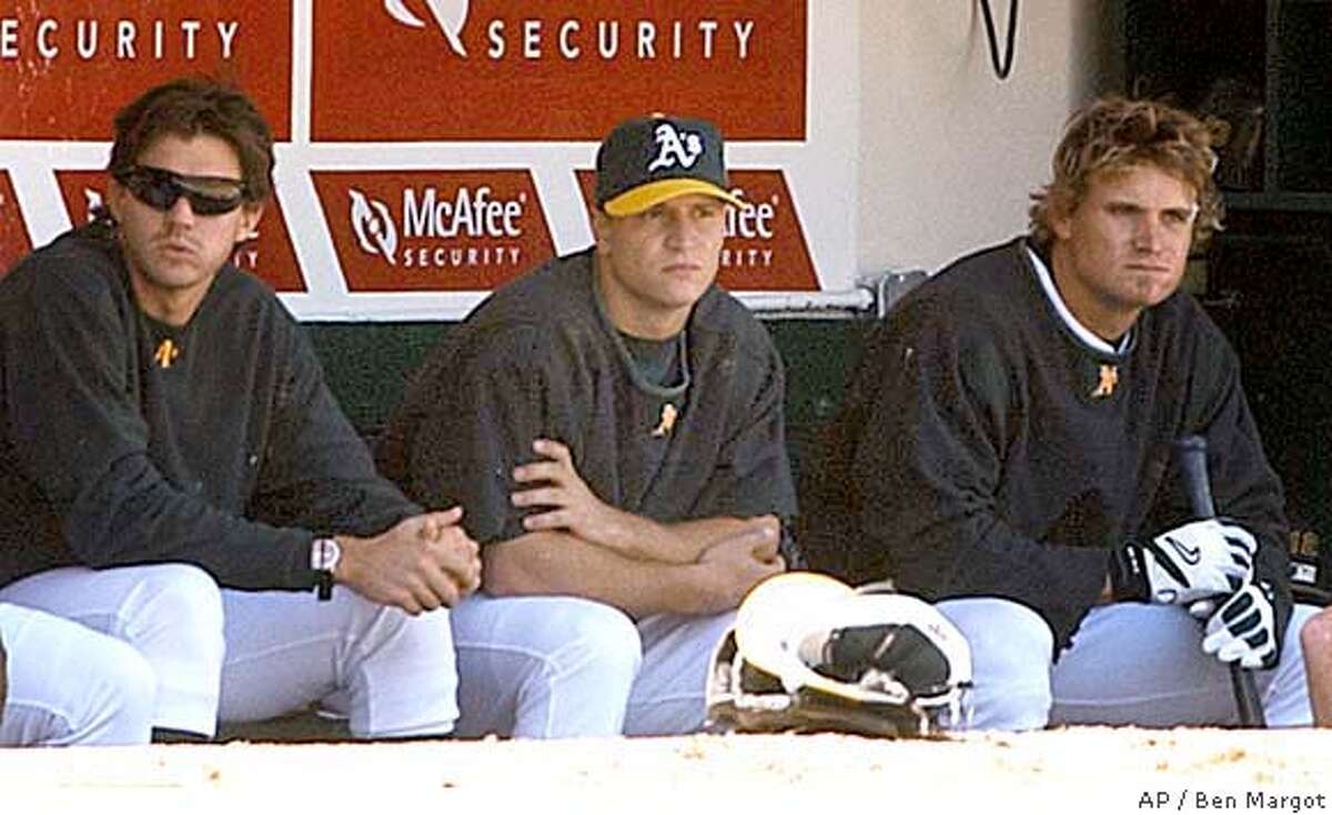 Oakland Athletics' Mark Ellis, center, sits in the dugout beside teammates Barry Zito, left, and Eric Byrnes during game against the Seattle Mariners, Saturday, April 10, 2004, in Oakland, Calif. Oakland Athletics second baseman Mark Ellis will miss the entire season with a right shoulder injury that requires surgery. Ellis, who has been rehabilitating in Phoenix, was in the Bay Area on Saturday to meet with team doctor Jerrald Goldman about the latest MRI on the shoulder. The test revealed a tornlabrum, and Goldman will perform the operation. (AP Photo/Ben Margot)
