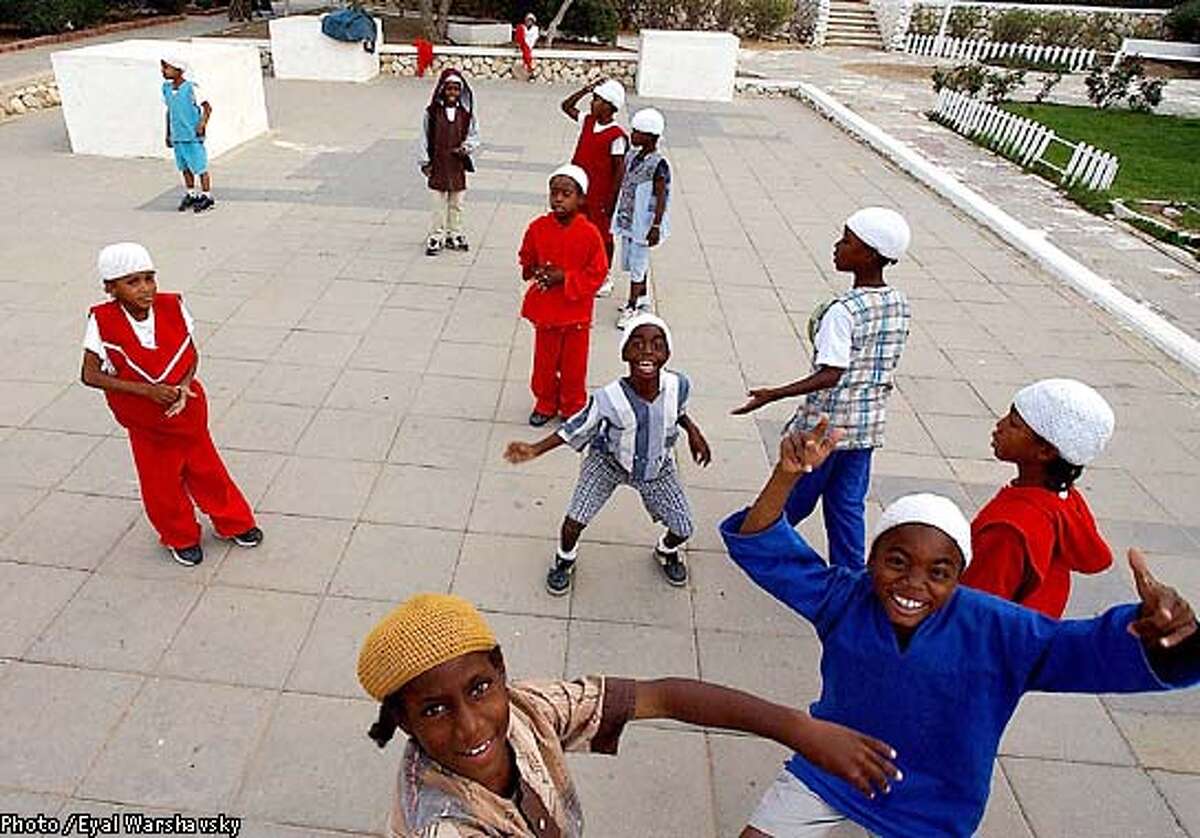 TO GO WITH STORY BY DANIELLE HASS--- Children from the Black Hebrew Community play in a playground in a communal area amidst the bungalows that have been home to the group for the past 32 years in Dimona Monday Oct 21 2002. The children, who have just finished school, cover their heads, as a sign of respect for their teachers. PHOTO BY Eyal Warshavsky/BAUBAU