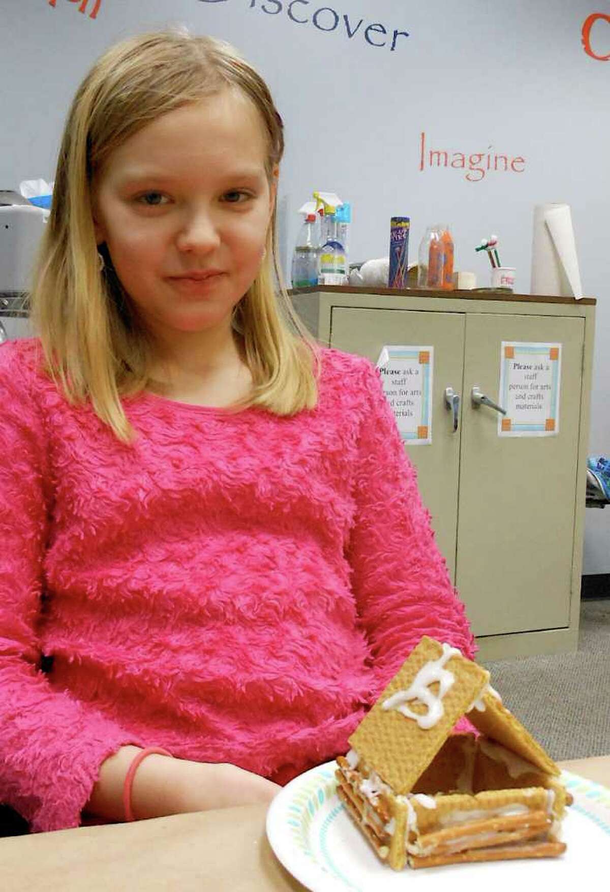 Nadia Roshenets, 10, sits with her completed edible log cabin at the "Cabin Fever" program Friday at the Fairfield Woods Branch Library.
