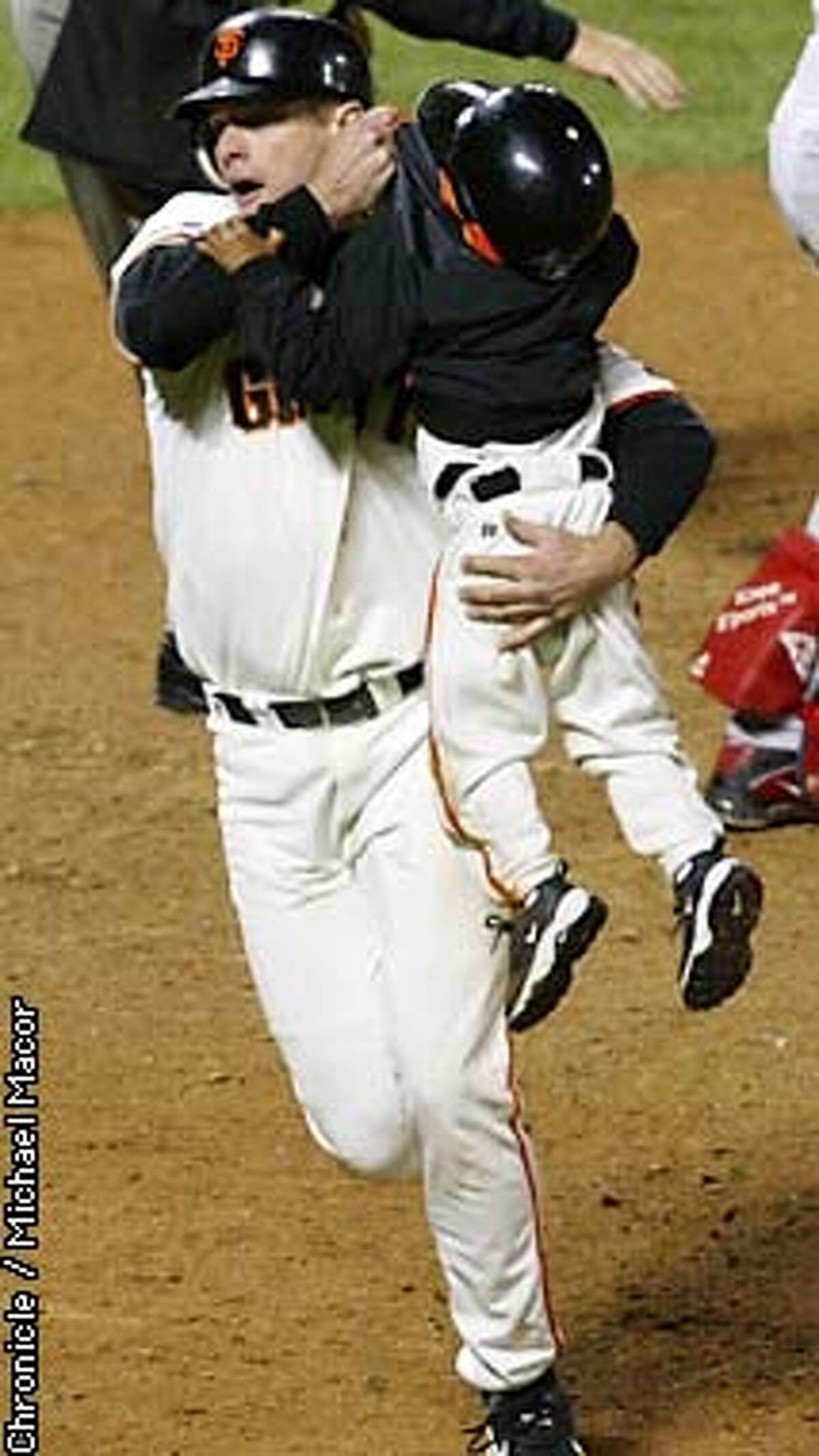 GIANTS67-C-24OCT02-SP-MAC --- J.T. Snow grabs a hold of Dusty Baker's 3-year old son Darren, as he came dangerously close to home plate as David Bell was about to cross the plate after Snow. The San Francisco Giants play the Anaheim Angels in Games 5 of the World Series at Pac Bell Park in San Francisco, Ca. October 24, 2002. Michael Macor/San Francisco Chronicle