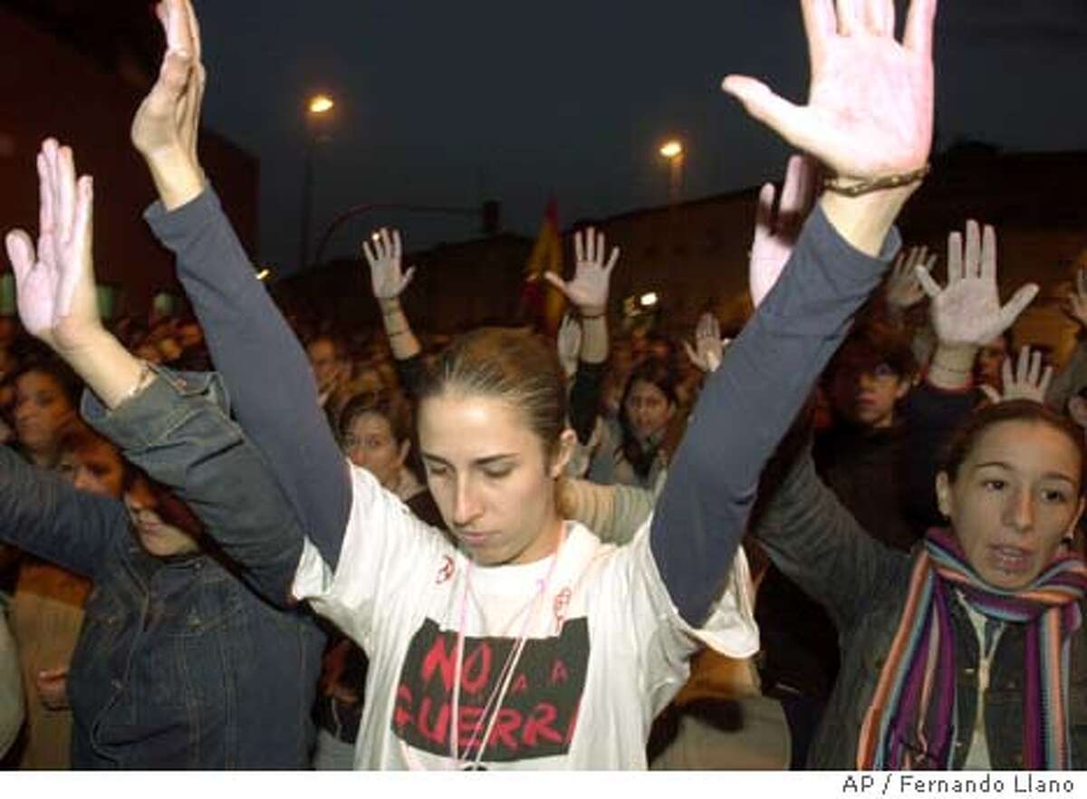 Protesters raise their arms during a silent march in Alcala de Henares, outside Madrid, Tuesday, March 16, 2004, to protest the bomb attacks on trains in the Spanish capital March 11, 2004, that killed 201 people and injured at least another 1,500. (AP Photo/Fernando Llano)