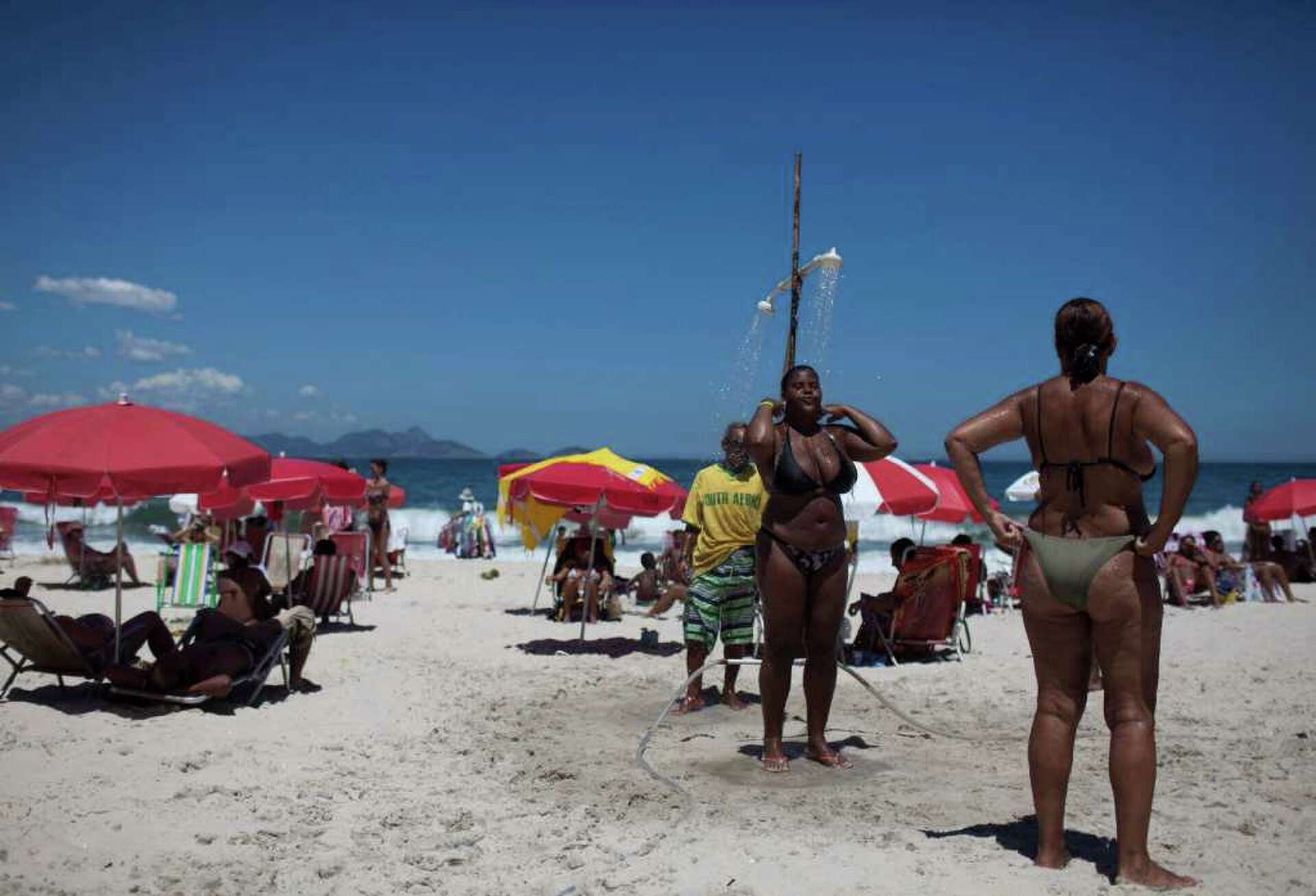 Brazilian girls taking shower on Ipanema beach In Brazil, bikinis adapting