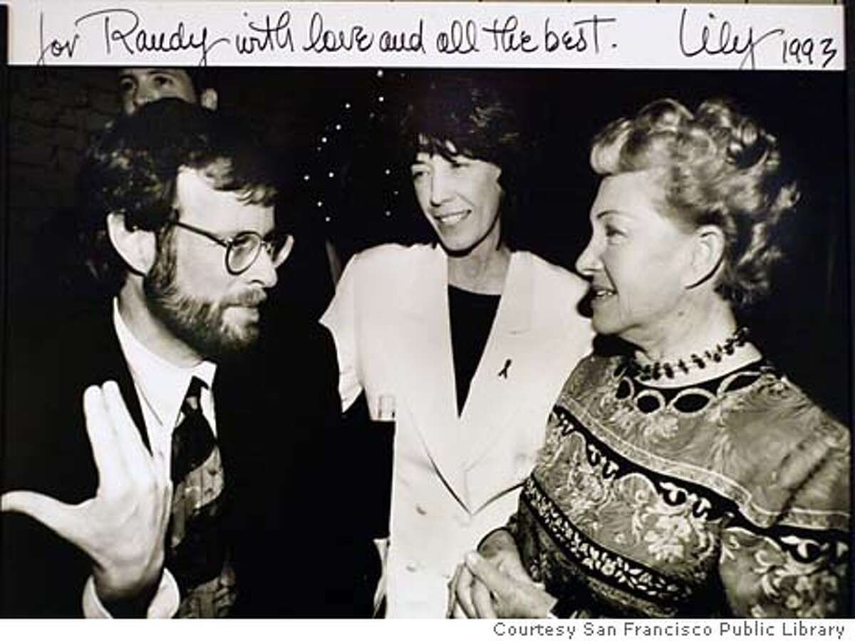 Former San Francisco Chronicle staff writer and author of The Band Plays On, Randy Shilts, talks with comedian Lily Tomlin and a unidentified women in this file photo dated 1993 Photo Curtasy San Francisco Library and Lily Tomlin. Editors Note: We only have permition from the Libraray to use this image. They have no idea who the photographer was or who may own the rights to the image.
