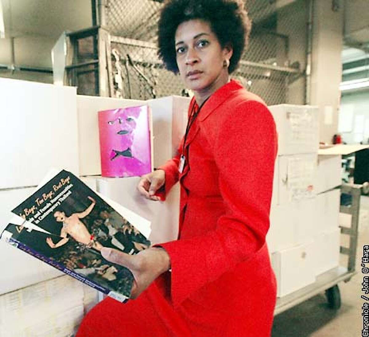 Police Inspector Milanda Moore show two books that were vandalized at the Libary by John Perkyns. He vandalized more than 600 books in all. Moore is holding a title "Becoming Visible An illistrated history of lesbian and gay life in the twenteth century. photo taken in the hall of Justice property room. Photo/John O'Hara