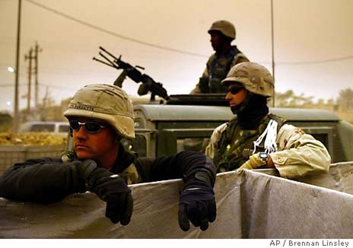 As a sandstorm moves in over central Iraq, U.S. soldiers man a checkpoint near the Iraqi Police Academy complex, in Baghdad, Iraq, Sunday, Feb. 15, 2004. (AP Photo/Brennan Linsley)