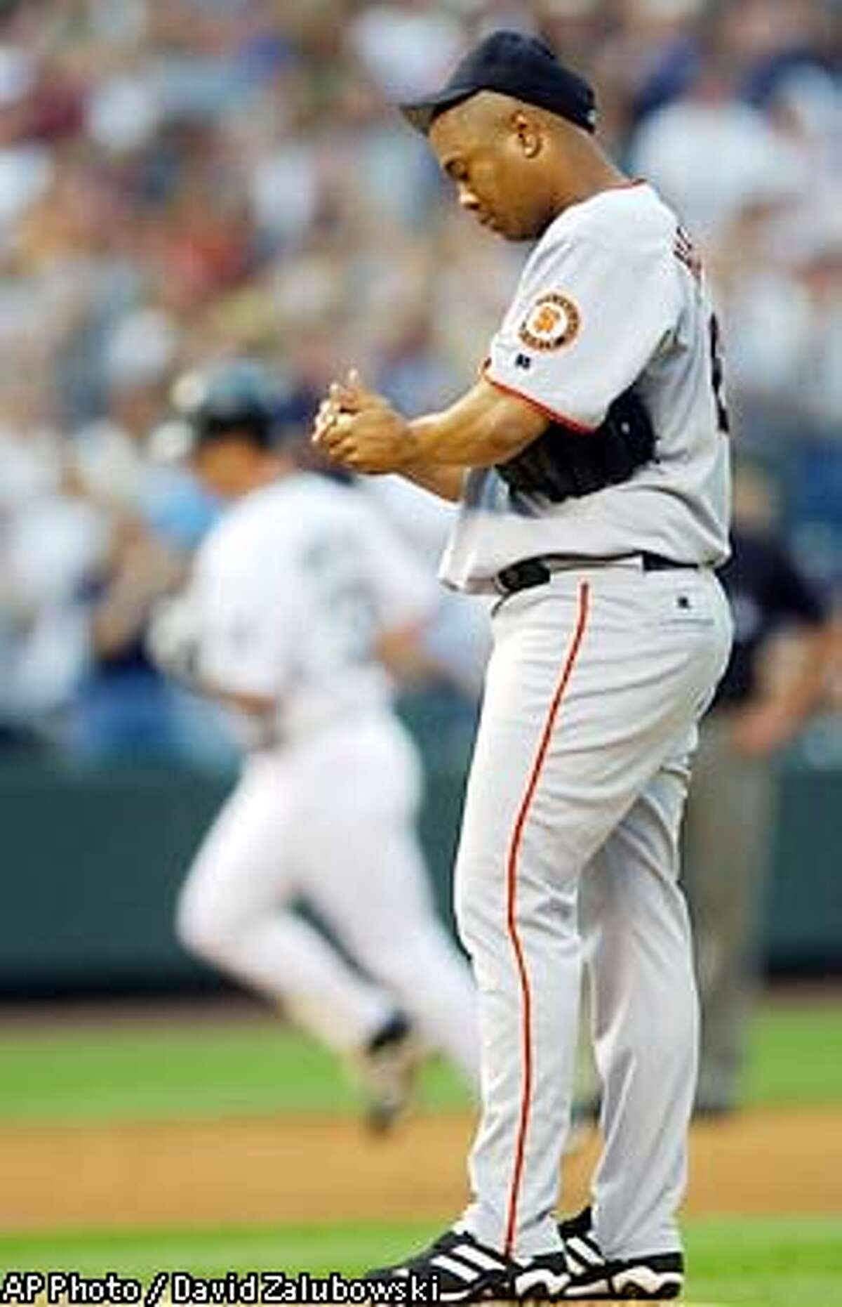 As Colorado Rockies' Larry Walker, back, circles the bases after hitting a three-run home run, San Francisco Giants starting pitcher Livan Hernandez rubs up a new ball in the second inning in Coors Field in Denver on Wednesday, July 3, 2002. Hernandez gave up seven runs in the inning before being pulled. (AP Photo/David Zalubowski)