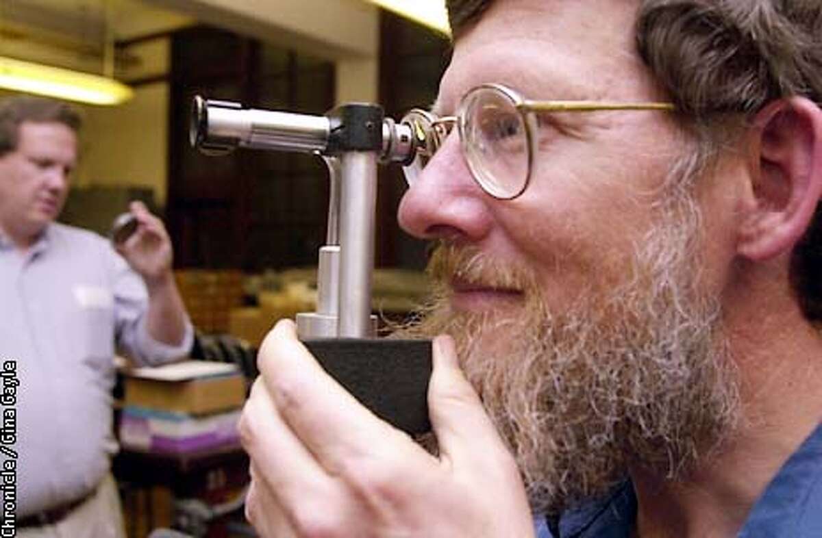 Tom Colton, a UC Berkeley Staff member, checks out an instrument that is used to measure the index of refraction as Bob Jacobson inspects another item. This and other items are being auctioned by the Physics Department. Photo by Gina Gayle/The SF Chronicle.