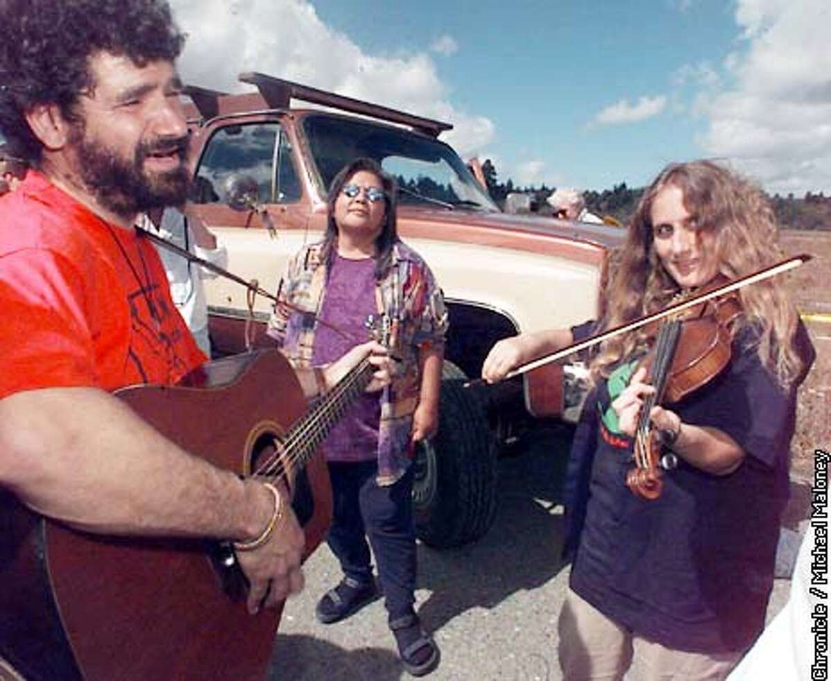 Carlotta, Humboldt County Earth First!'s Darryl Cherney (left) and Judi Bari (right) practice behind the stage prior to entertaining the crowd with their music. Carol Williams of Klamath is in center. Around 3,000 demonstrators gathered at Pacific Lumber Company's Carlotta Mill to protest the possible logging of the Headwaters forest of ancient redwood groves. Photo by Michael Maloney