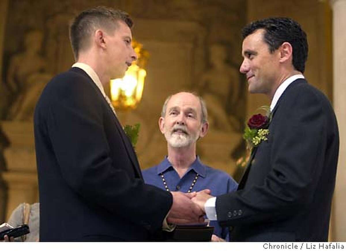 David Knight, right, the estranged son of state Sen. William "Pete" Knight, who authored California's law banning same-sex marriage, holds hands with his long-time partner, Joe Lazzaro, left, as they take their wedding vows, Tuesday, March 9, 2004, at City Hall in San Francisco. Performing the service is Donald Bird, center. (AP Photo/The San Francisco Chronicle, Liz Hafalia)