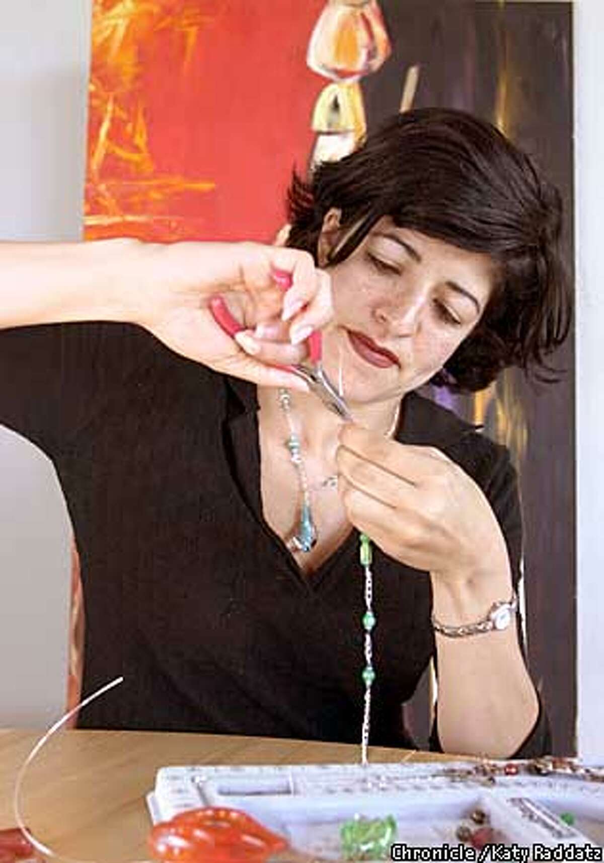 PHOTO BY KATY RADDATZ--THE CHRONICLE Keren Barukh (cq) makes jewelery at her home in Concord. SHOWN: Keren working on a necklace. Painting in background. also by Barukh, is called "African Woman." Keren wearing necklace of blown glass drop with turquoise--other stones are Austrian crystals and turquoises.