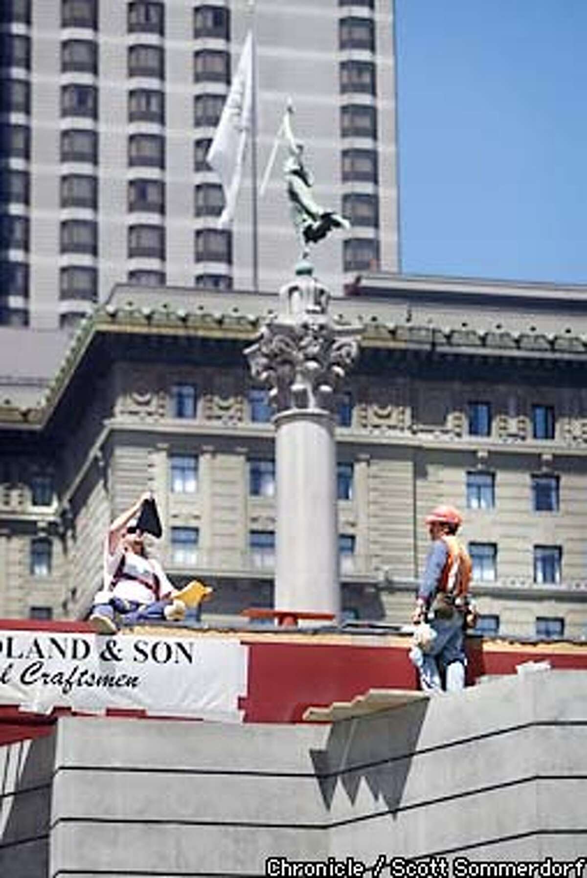 Busy construction workers attend to their duties on the Union Square renovation with the Dewey Memorial column in the background. (SF CHRONICLE PHOTO BY SCOTT SOMMERDORF)