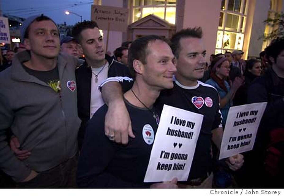 Left to Right: Derek Jentzsch and Cody Hoyer (behind) andTony Mason Asa Cairnas with "I love my Husband" signs, listen to the speakers at the protest. Protest in the Castro District against the proposal by Pres. Bush to amend the constitution to prohibit same sex marriages. John Storey/The Chronicle