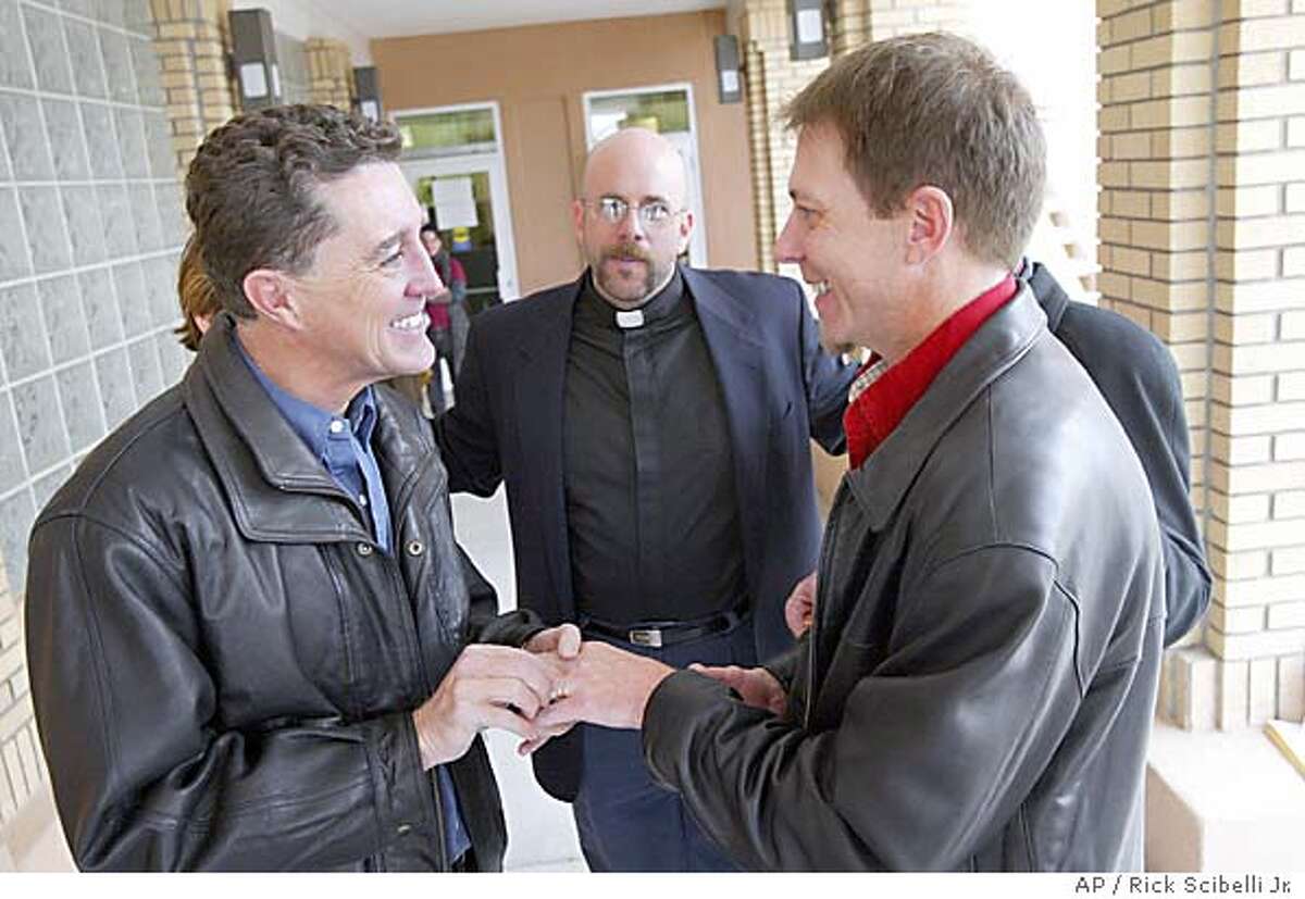 James Walker, places a ring on his parter, Michael Palmer, while trading vows under the direction of reverend David Gant, center, Friday afternoon, Feb. 20, 2004 in the back of the Sandoval County Court House in Bernalillo, NM. Sandoval County starting issuing marriage lisences to same sex couples Friday morning after the counties attorney deemed that New Mexico law was not clear and that refusing to issue the licenses to same-sex couples could open the county to legal liability.(AP Photo/Rick Scibelli Jr.)