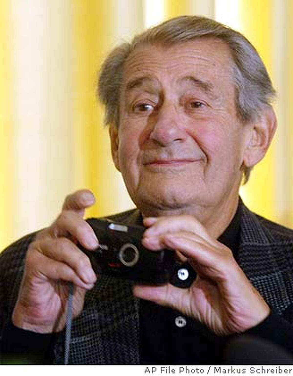 ** FILE ** German born photographer Helmut Newton holds a camera during a news conference after signing the contract for the Newton-Foundation in Berlin, in this Oct. 22, 2003 file photo. Newton was killed in a car crash Friday, Jan. 23, 2004 police said in Hollywood, Calif. He was 83. Newton, a fashion photographer whose work appeared in magazines such as Playboy, Elle and Vogue, was best known for his stark, black and white nude photos. (AP Photo/Markus Schreiber)
