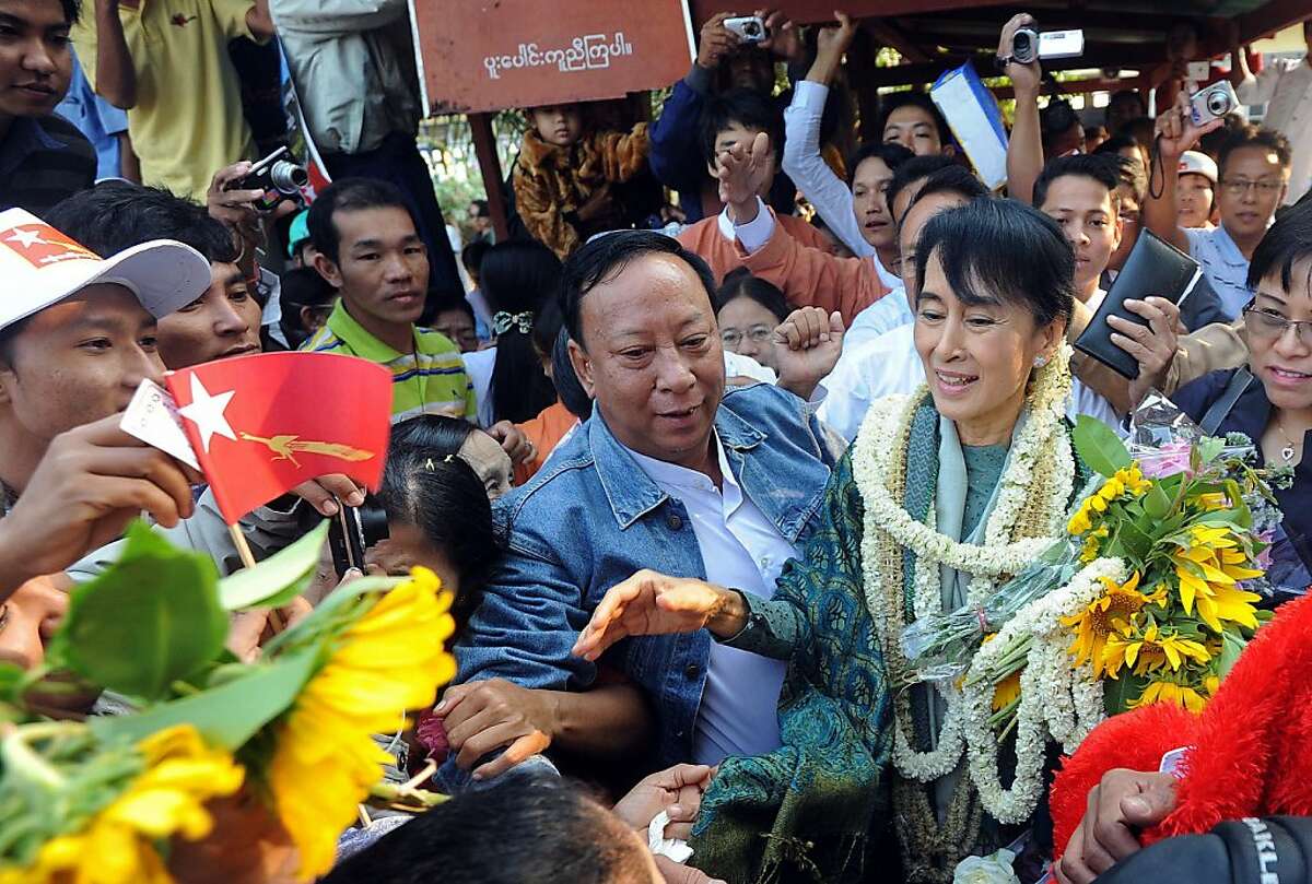 Myanmar opposition leader Aung San Suu Kyi (R) is greeted by supporters as she arrives to address a gathering as part of her campaign trail on the outskirts of Myanmar's southern city of Dawei on January 29, 2012. Huge crowds lined the streets to greet Suu Kyi as she hit the campaign trail on January 29 ahead of by-elections seen as a key test of the regime's commitment to reform. AFP PHOTO/Soe Than WIN (Photo credit should read Soe Than WIN/AFP/Getty Images)