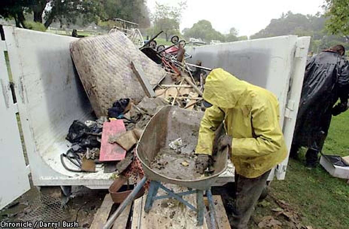 A worker throws out junk and trash to be hauled away from Camp Paradise, a homeless squatters camp now abandoned because of the flooding near the San Lorenzo River in Santa Cruz. Some of the squatter's belongings were saved by the camp residents, and taken away to be stored. Chronicle Photo by Darryl Bush