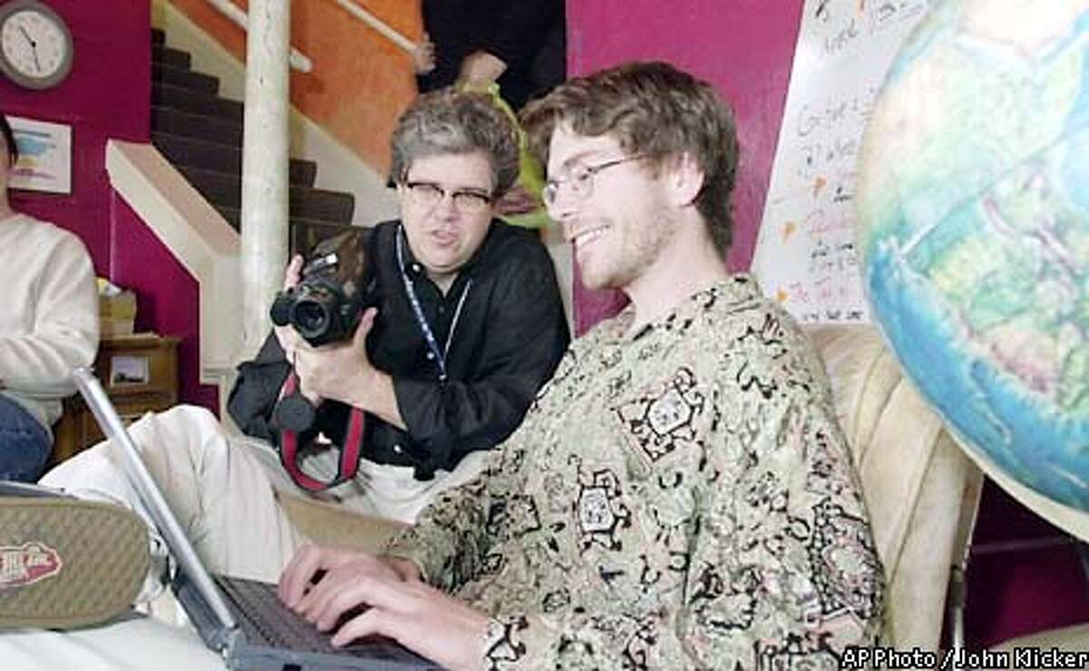 Ken Anderson, center, an anthropologist with Intel, uses a video camera to document wireless online use by Greg Haines at the Hawthorne Youth Hostel, Thursday, April 11 2002, in SE Portland, Ore. Anderson said that Intel chose the Youth Hostel because it is a transient group of young and elderly travelers both domestic and international. "They are the non-road warrior wireless user's", Anderson say's, "Different than the Marriot Crowd." Intel donated a WiFi wireless access point to the hostel in order to conduct the study. (AP Photo/ John Klicker)
