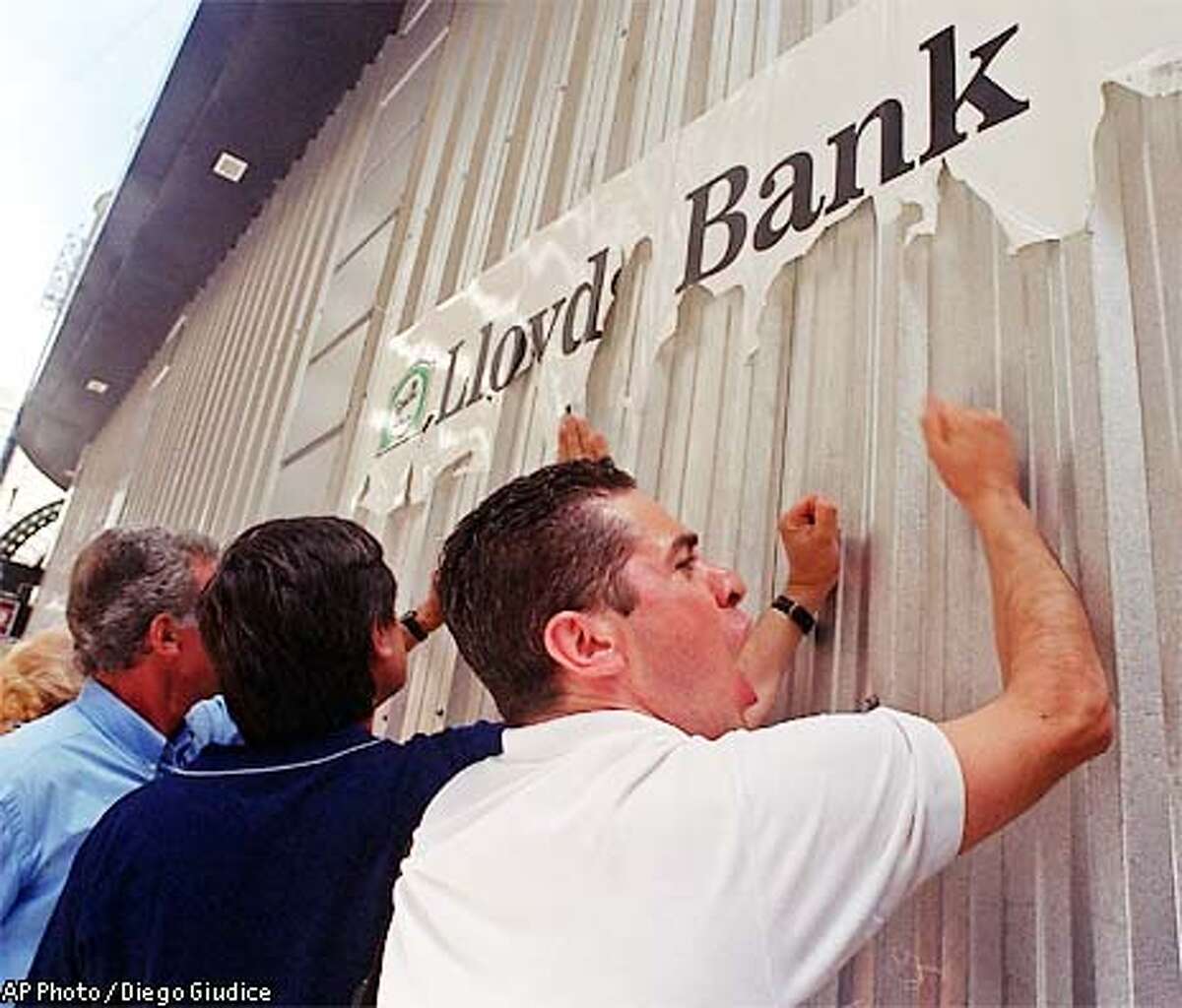 Demonstrators bang on the door of a branch of Lloyds Bank in the financial district of Buenos Aires, Friday, Feb. 8, 2002. Demonstrators were asking to get back dollars instead of the Argentine pesos that they will receive. (AP Photo/Diego Giudice)