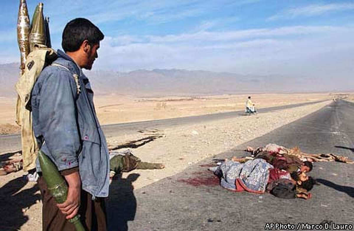 A northern alliance fighter carrying rockets on his shoulders stops to look at the dead bodies of Taliban soldiers along the road leading into Afghanistan's capital Kabul, Tuesday, Nov. 13, 2001. Afghan opposition fighters rolled into Kabul on Tuesday after Taliban troops slipped away under cover of darkness, leaving the capital without a fight. AP Photo / Marco Di Lauro