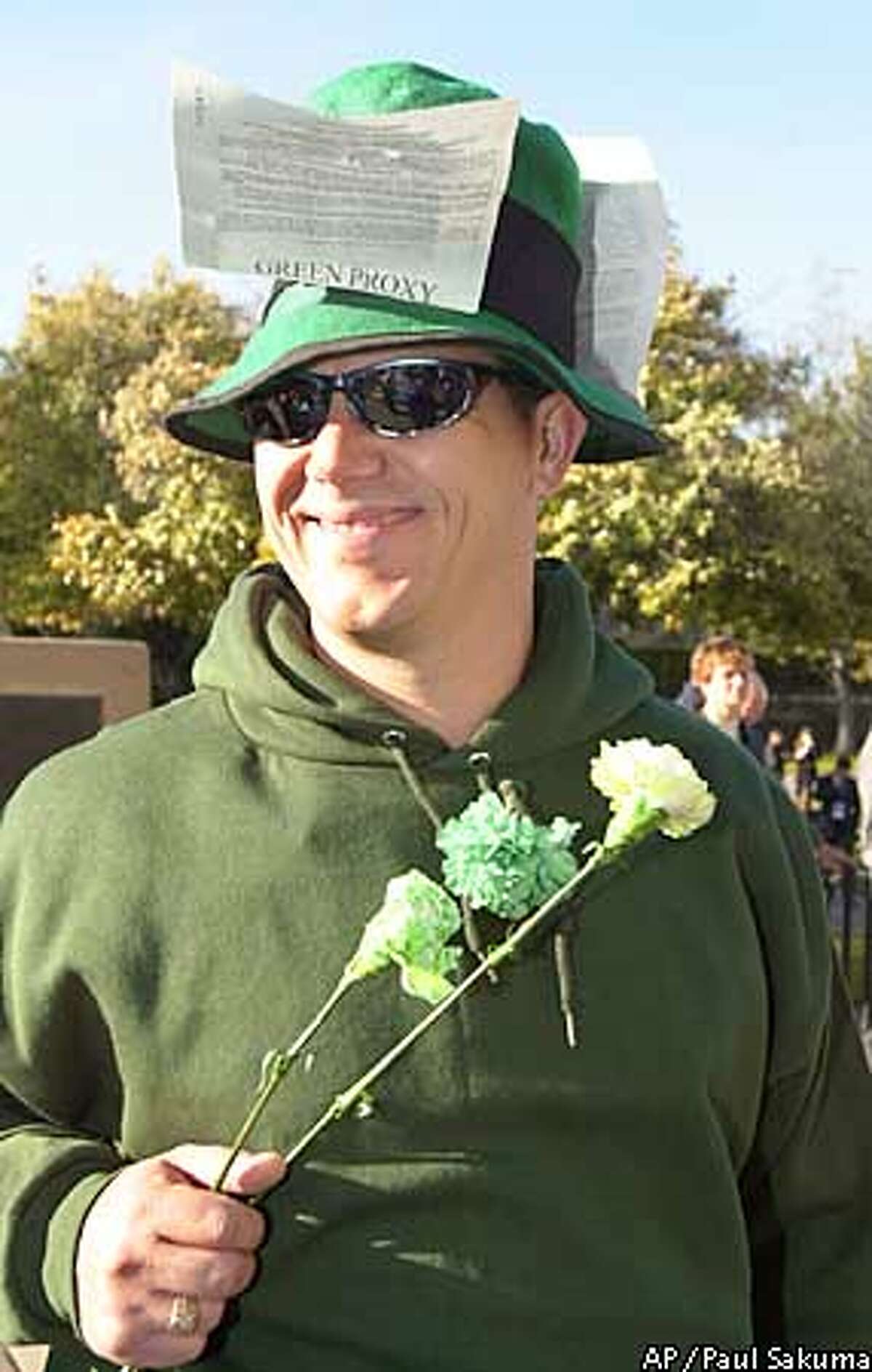 Hewlett Packard Company shareholder Lyle Ohm, of Livermore, Calif., smiles as he wears a Green Proxy card and passes out green flowers to HP shareholders before the meeting in Cupertino, Calif., Tuesday, March 19, 2002. The proxy fight over the $21 billion acquisition of Compaq Computer Corp. by HP gave individual investors a rare chance to directly influence the fate of two companies. HP's shareholder vote on the deal Tuesday. The Green Proxy was against the merger. (AP Photo/Paul Sakuma)