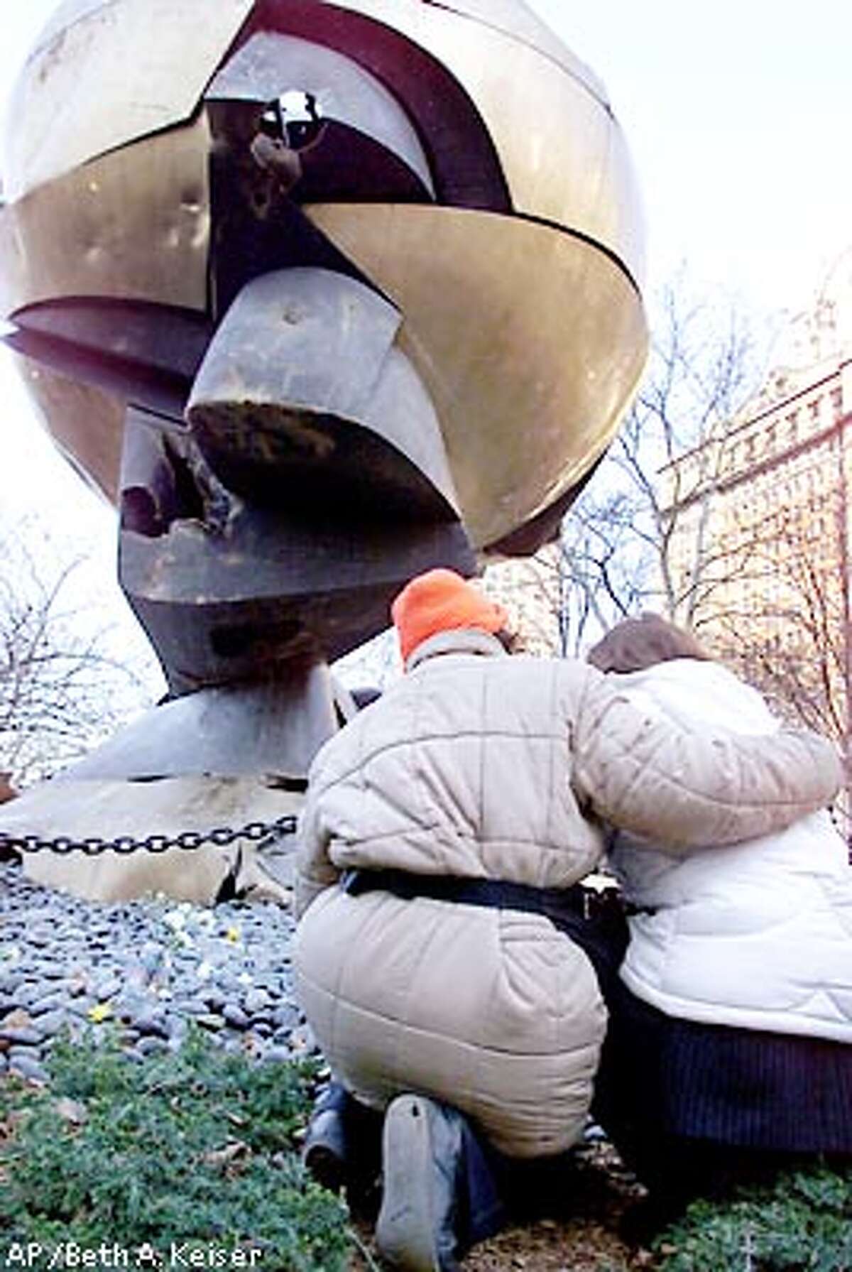 Carmen Valazguez, left, of the Red Cross comforts Jahada Slim, right, who lost a friend in the World Trade Center attacks as they kneel below "The Sphere" Monday, March 11, 2002 in New York. The bronze sculpture, which was a meeting point for workers at the World Trade Center before suffering a deep gash during the Sept. 11 terrorist attacks, was dedicated in a ceremony as a temporary memorial to the victims in Battery Park. (AP Photo/Beth A. Keiser)